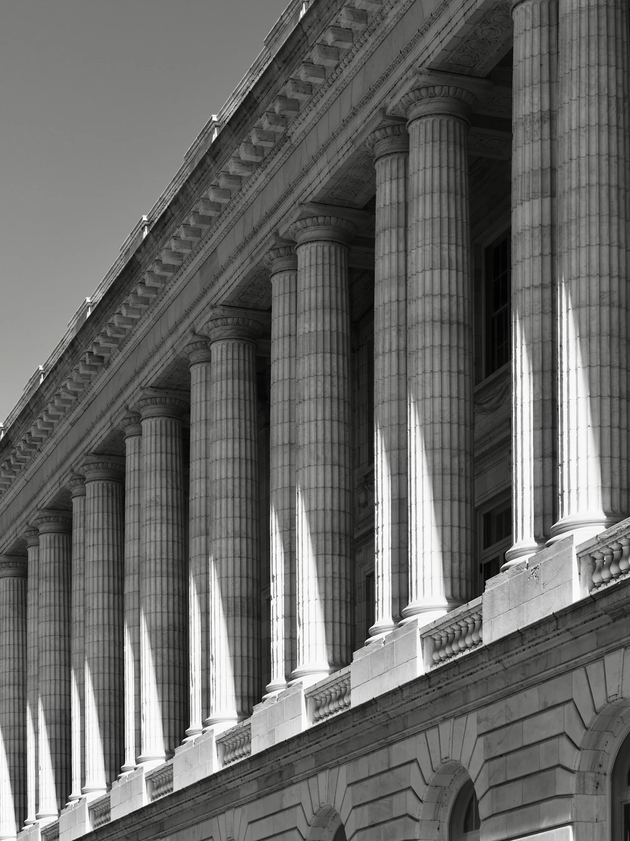 The columned facade of a neoclassical civic building in strong sunlight