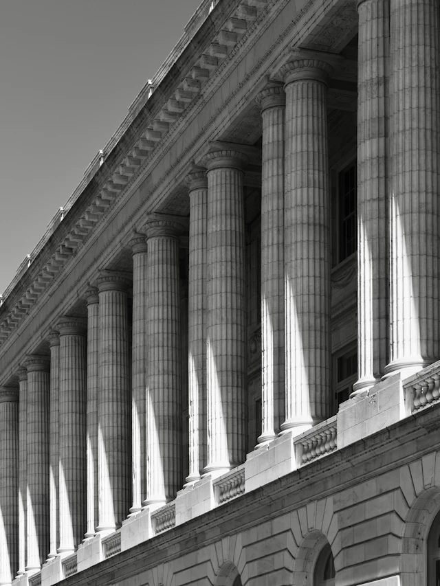 The columned facade of a neoclassical civic building in strong sunlight