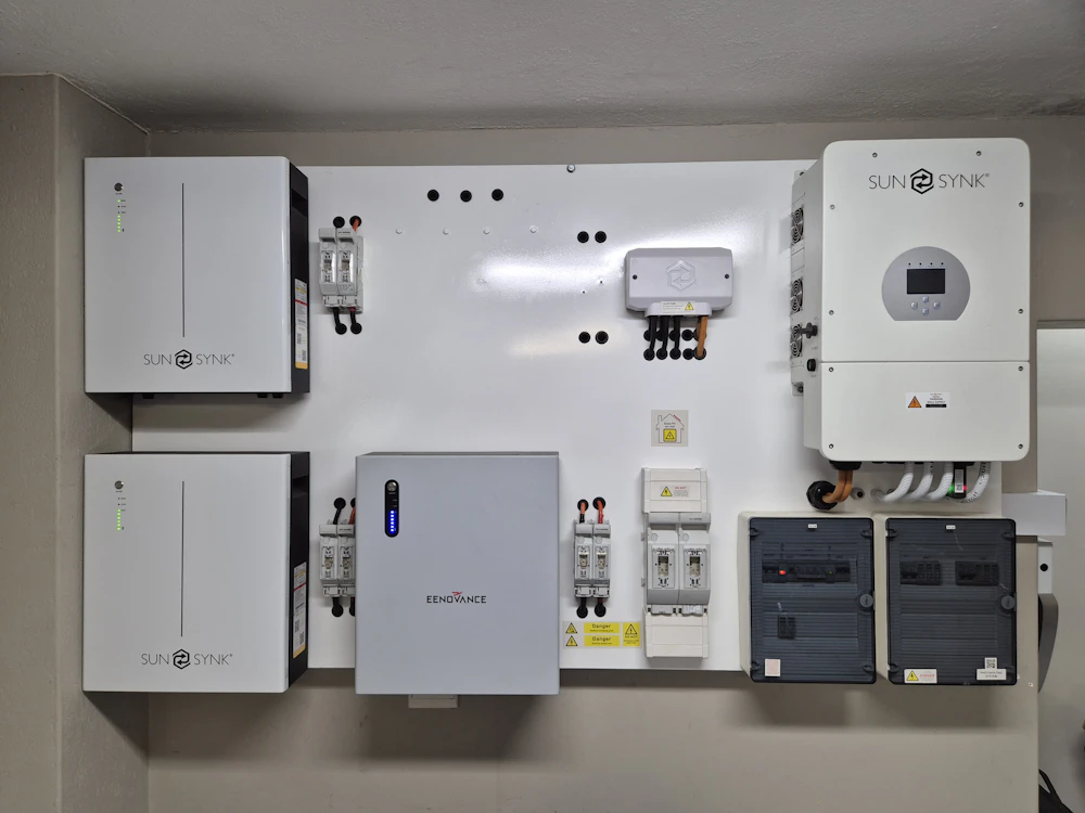 A wall-mounted home battery and inverter, cleanly installed and wired in a garage.