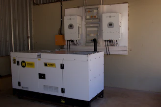 A large white generator next to wall-mounted power inverters