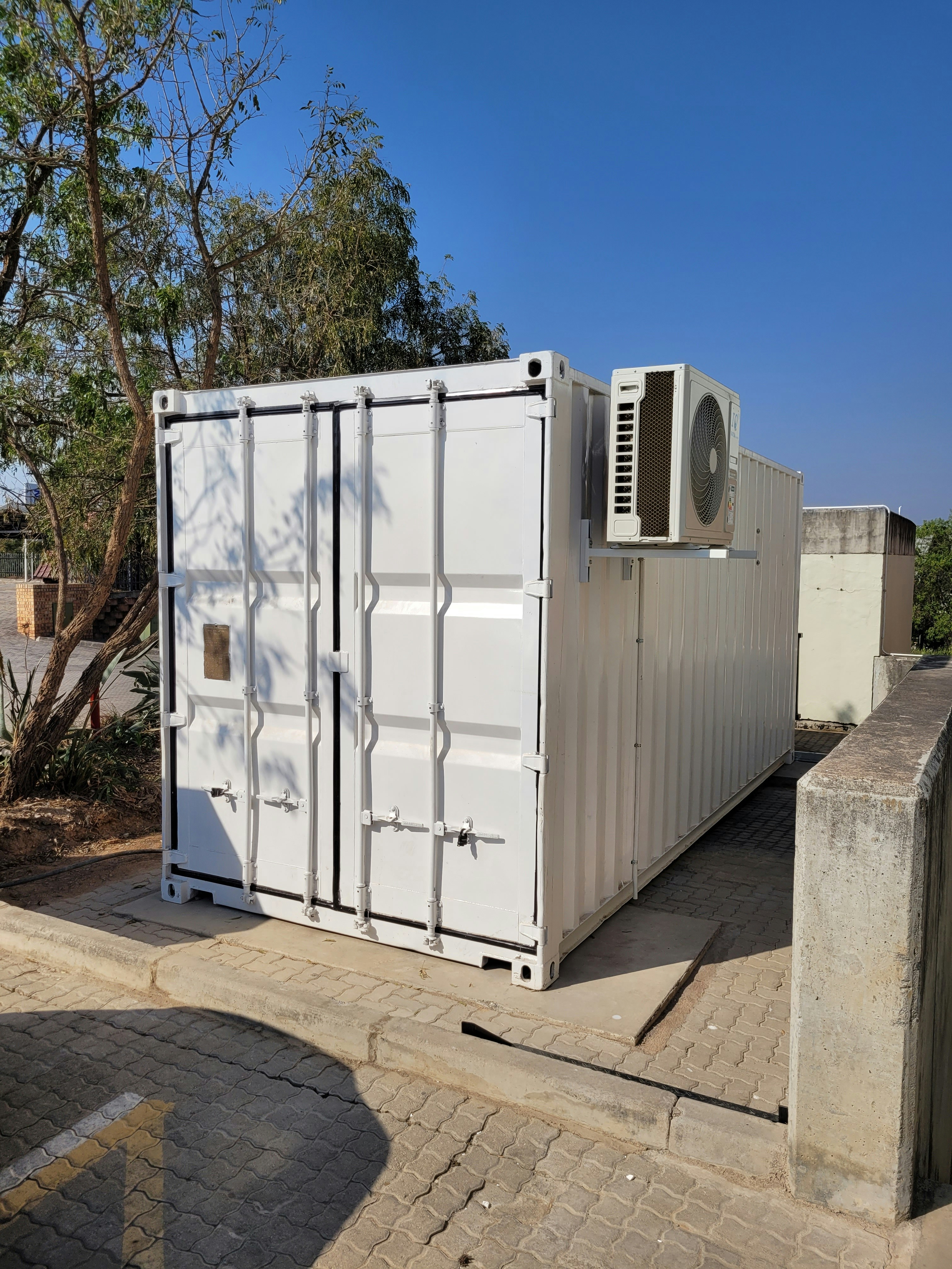 Serviced white container utility unit with an external HVAC condenser on site