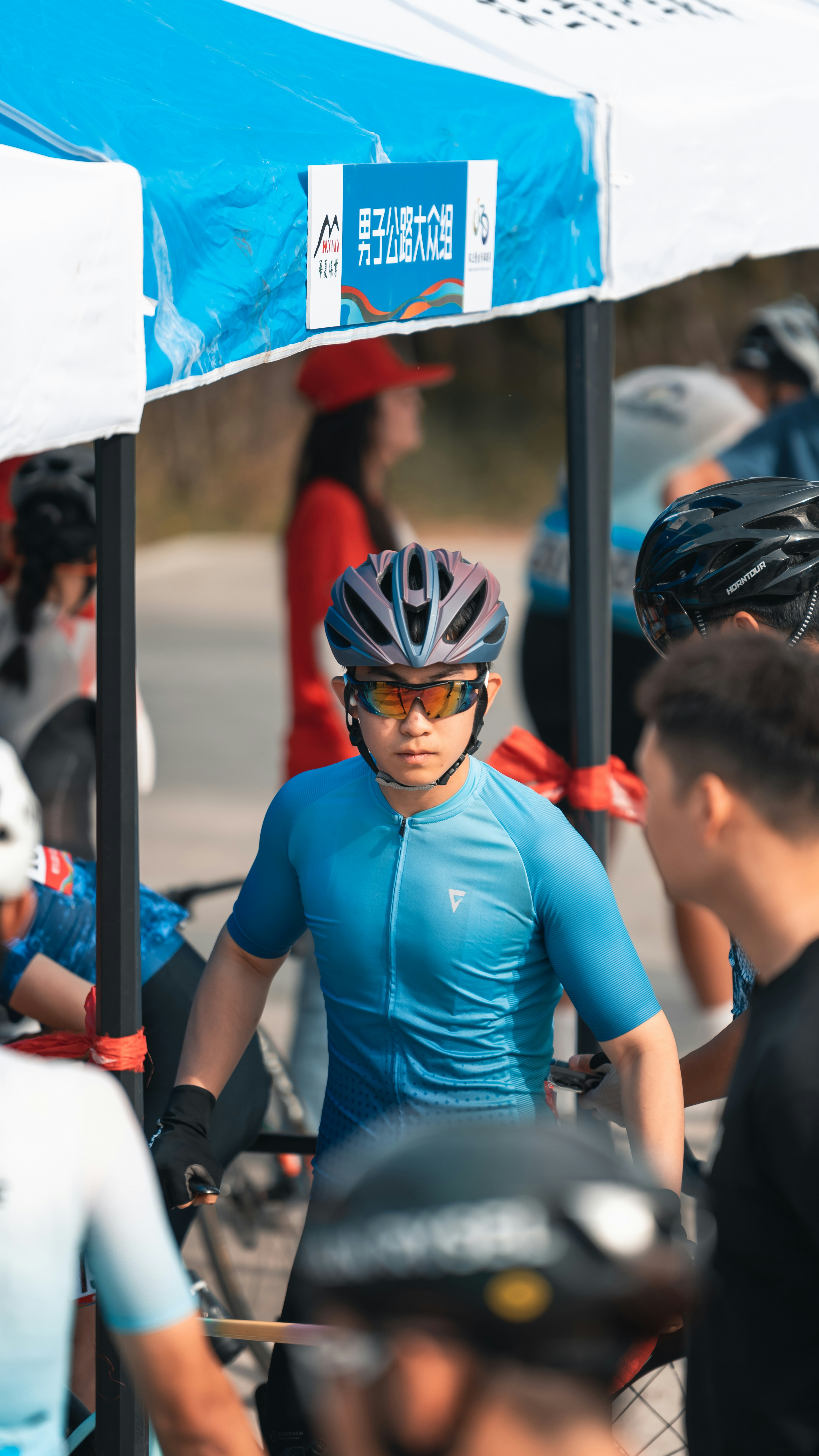 Male cyclist in blue jersey and helmet under a tent.