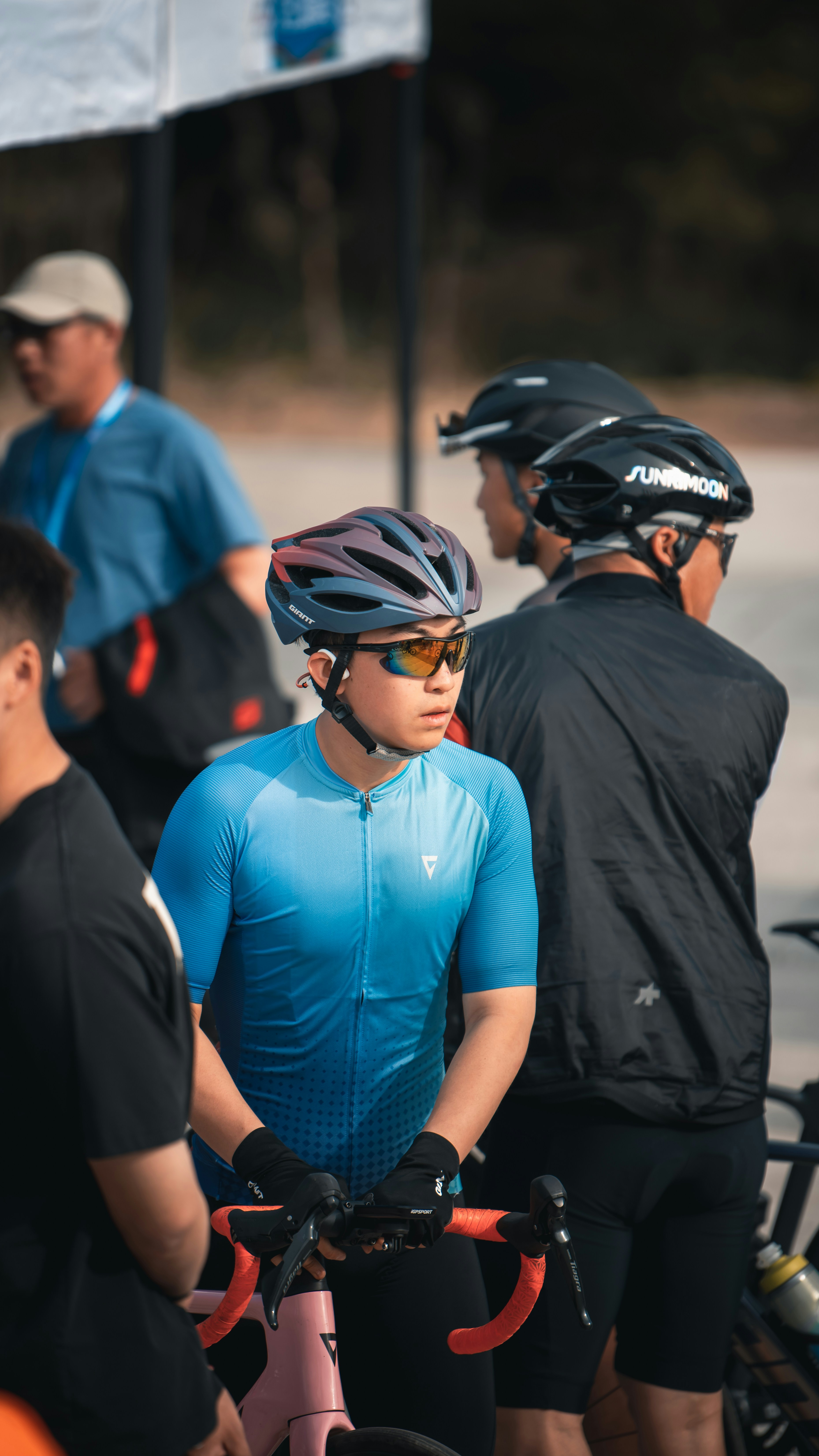 A cyclist wearing blue jersey and helmet holds a bike.