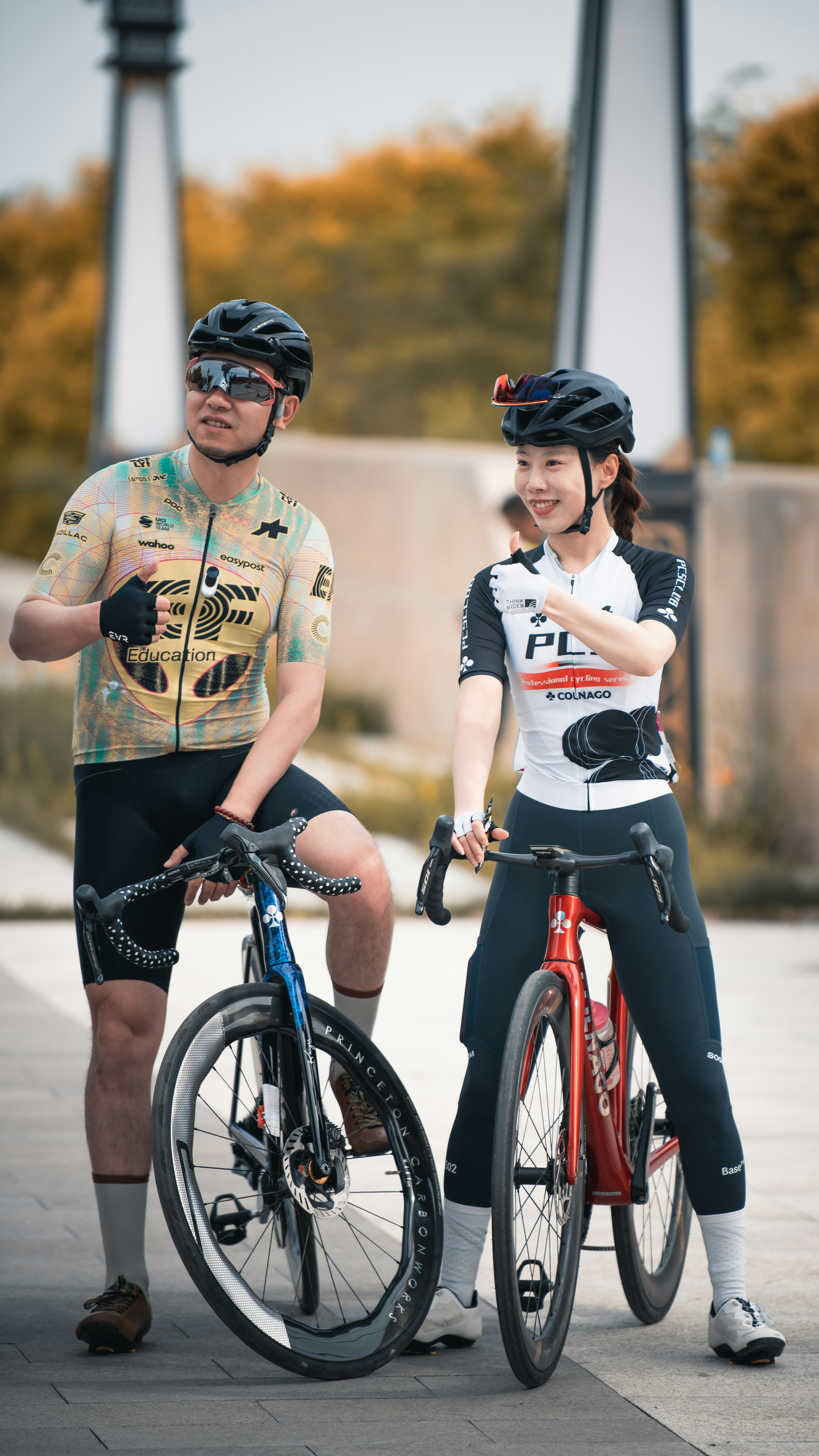 Two smiling cyclists stand with their road bikes.