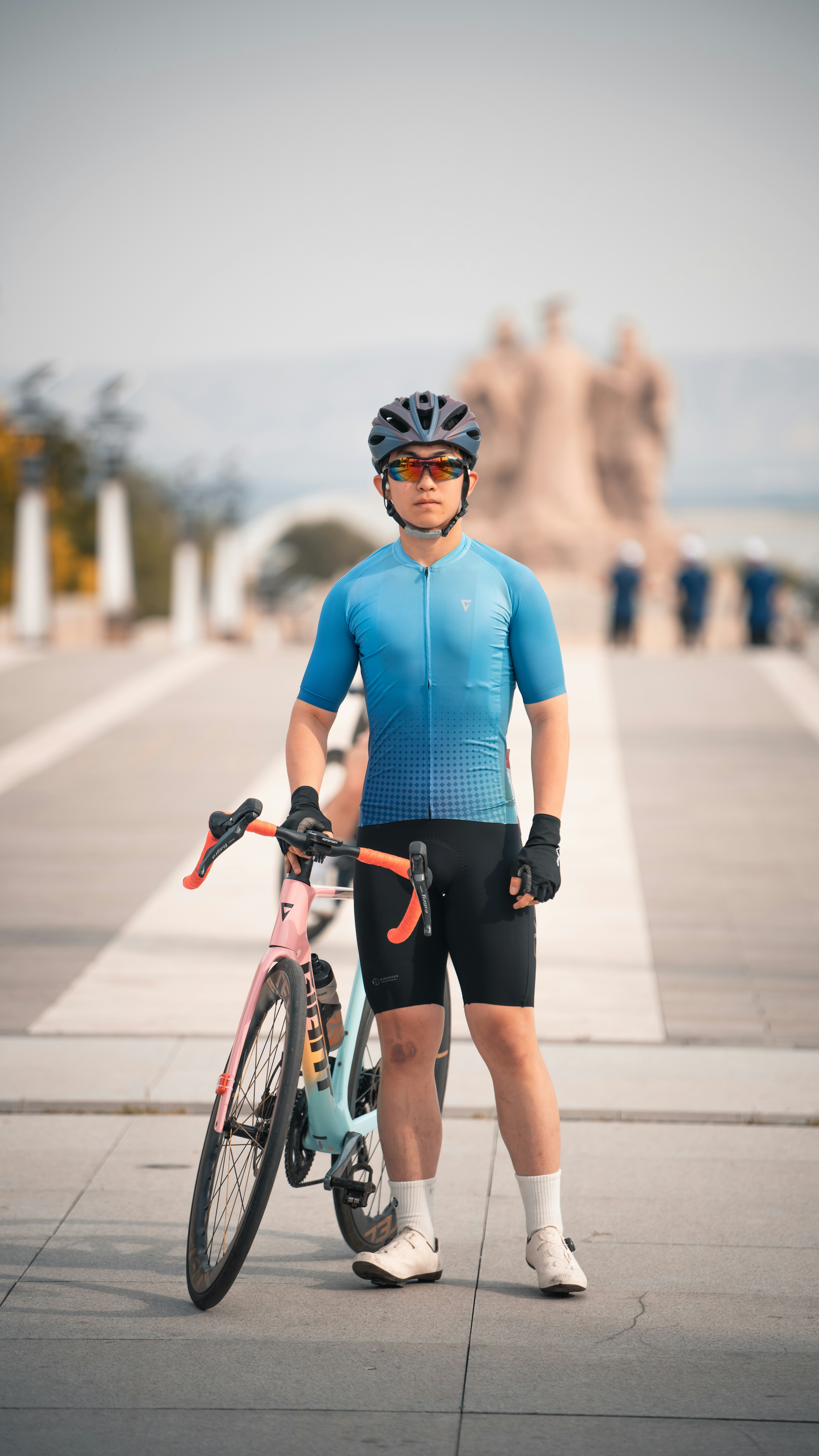Cyclist in blue kit and helmet stands beside bike.