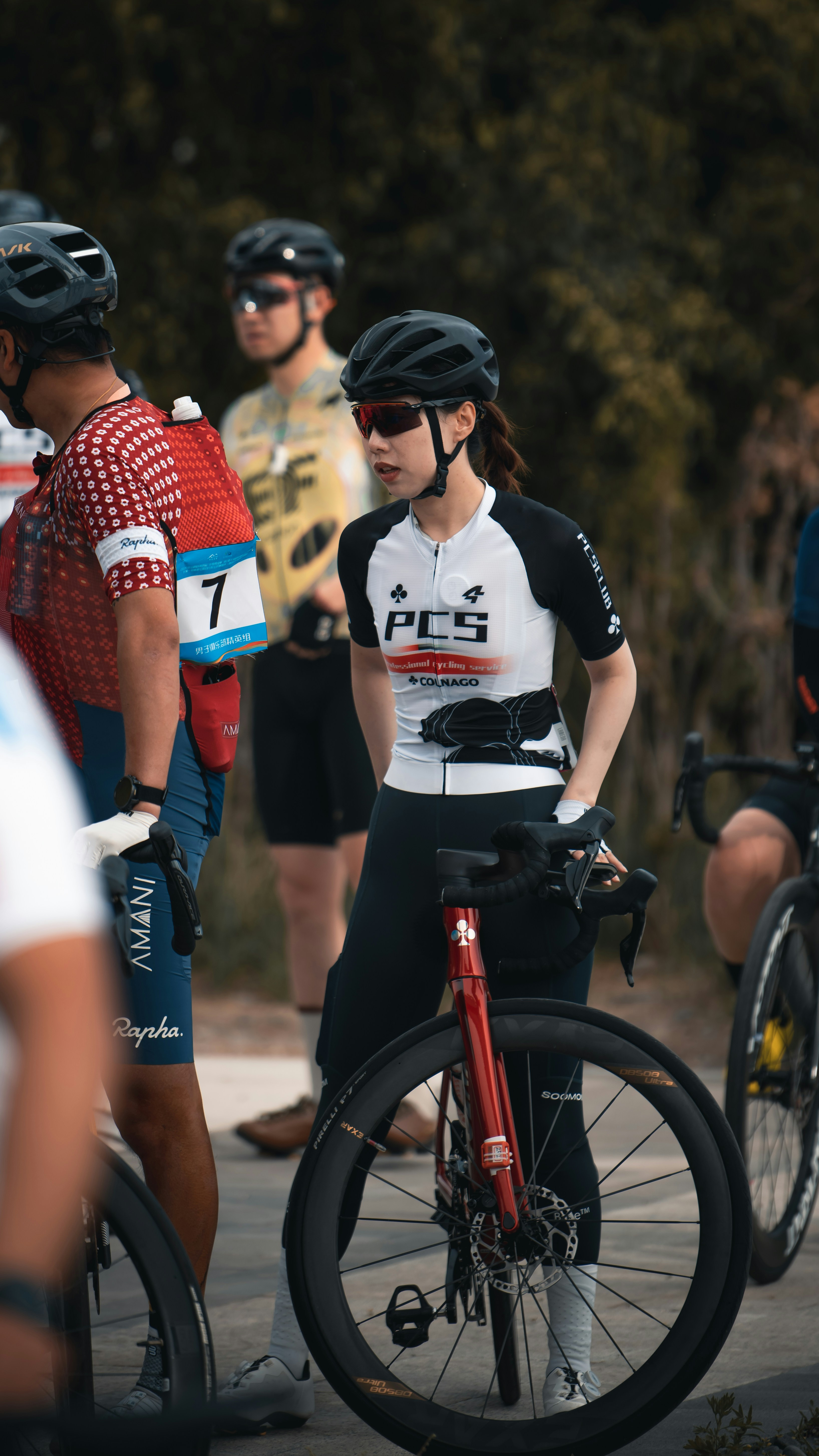 Female cyclist wearing helmet and sunglasses with her bike.