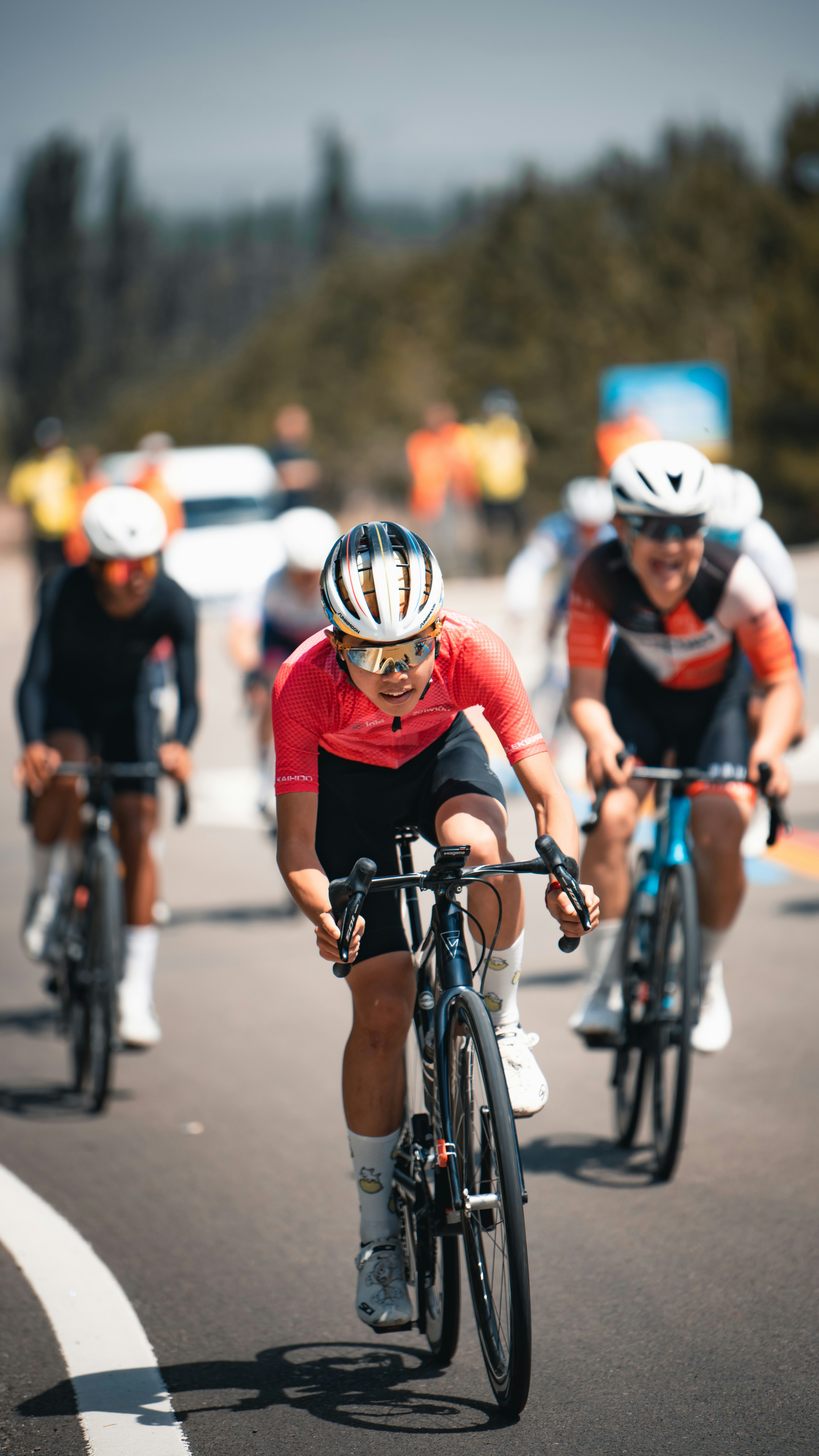Cyclist in pink jersey races on a sunny road.