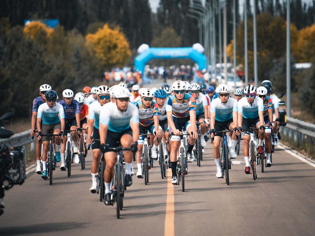 Cyclists race on a road under a blue arch