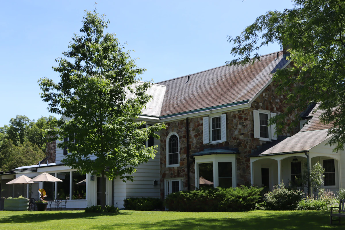 Stone and white transitional home with covered porch and mature trees at 9410 Grand Lake Estates Drive