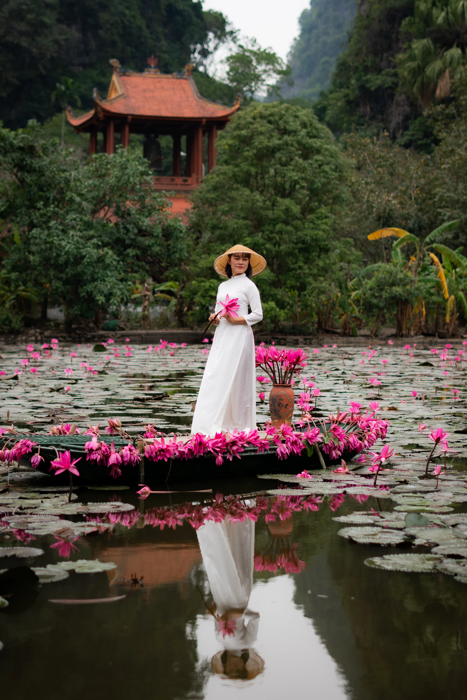 Traveller on a flower-filled boat in Ninh Binh, Vietnam