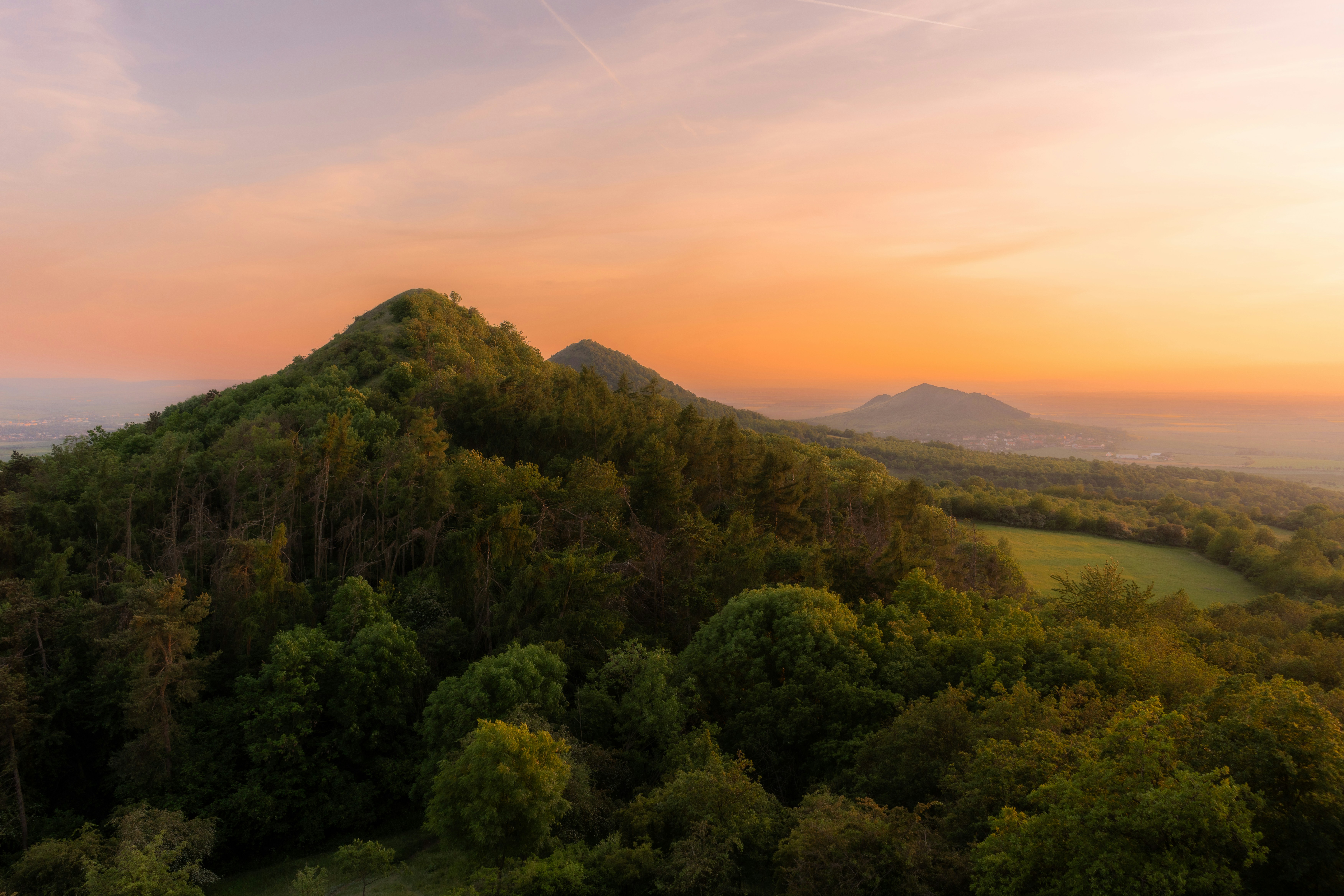 Forested hills at sunrise with an orange sky.