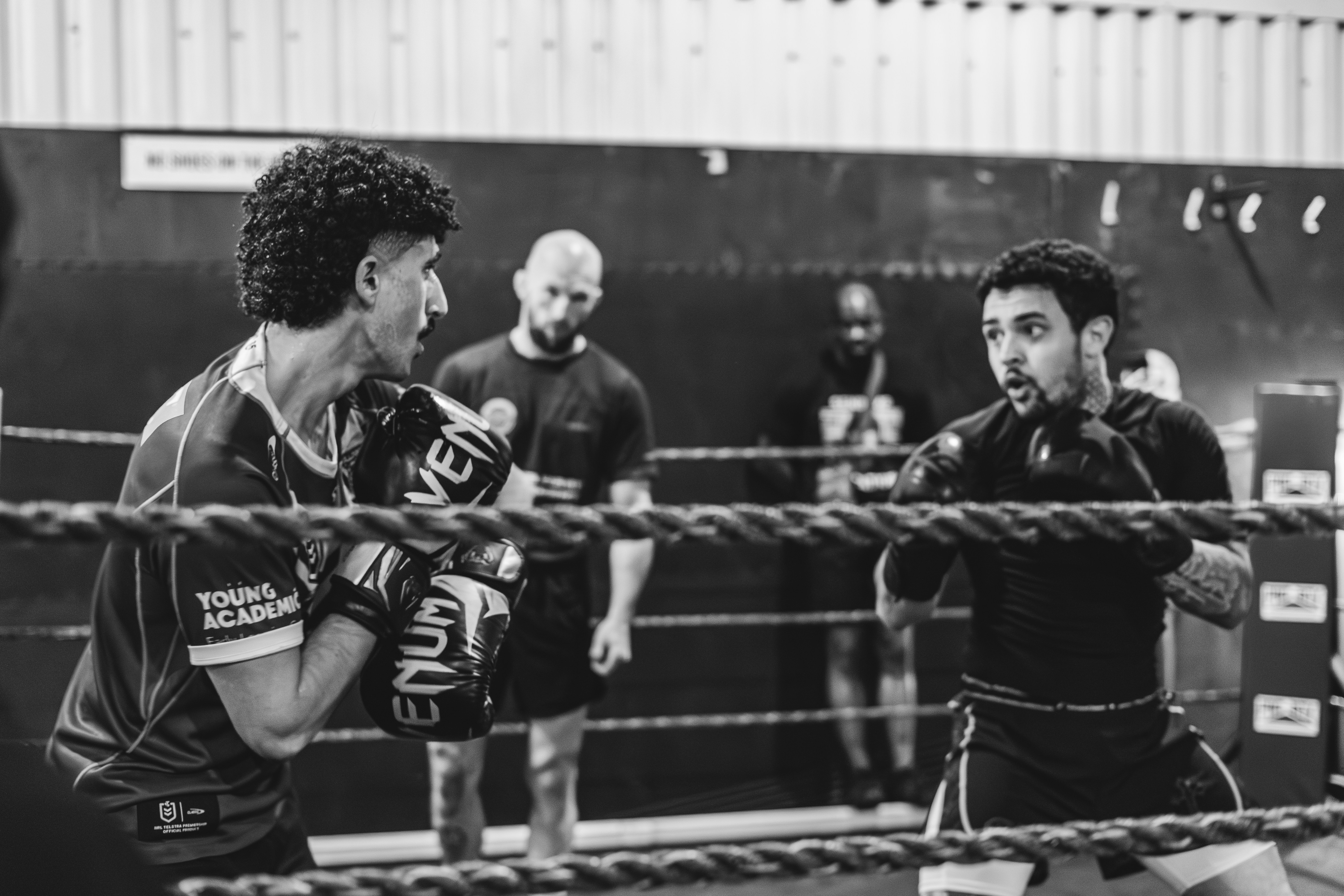 Two men boxing in a ring with spectators watching.