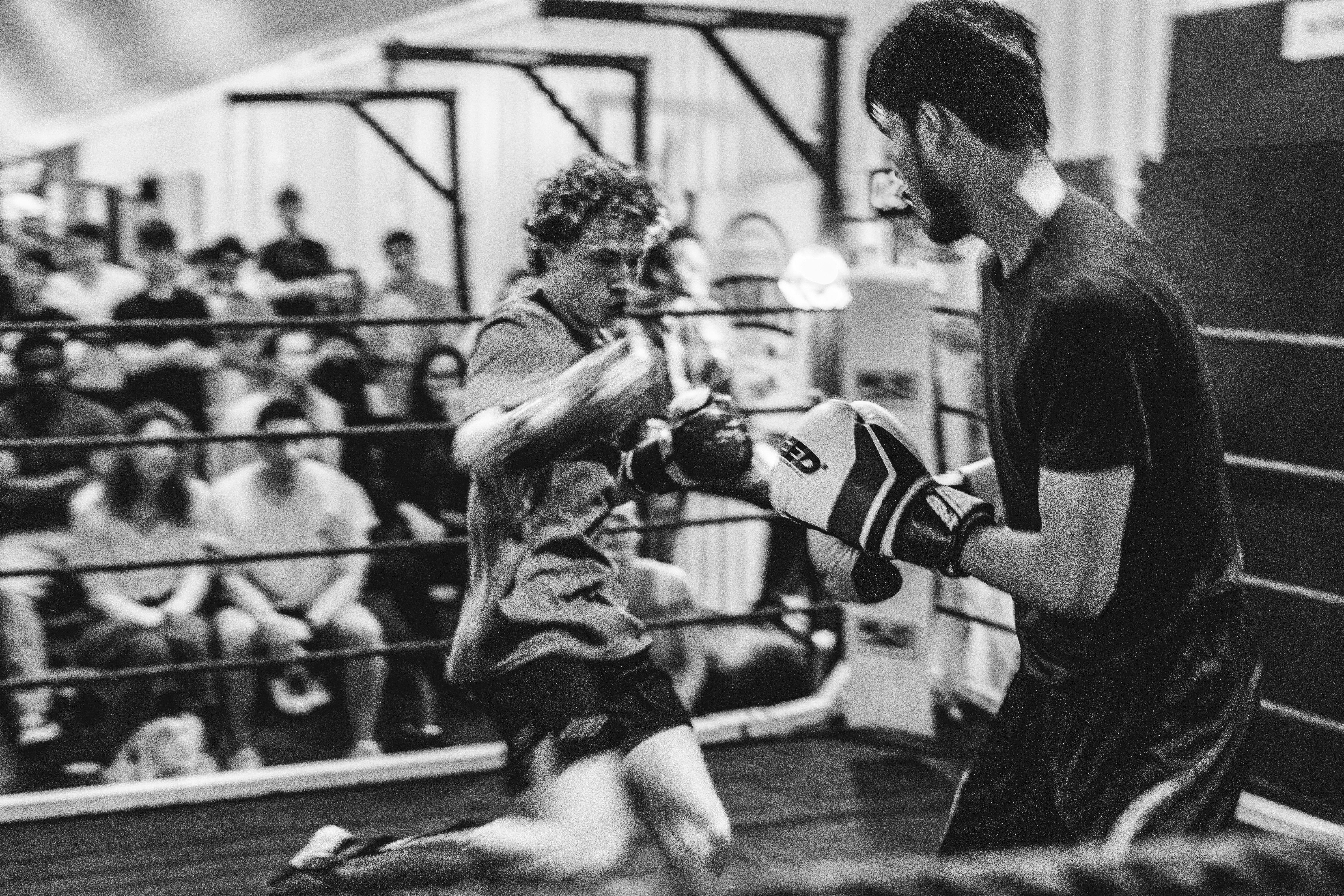 Two men boxing in a ring with spectators watching.