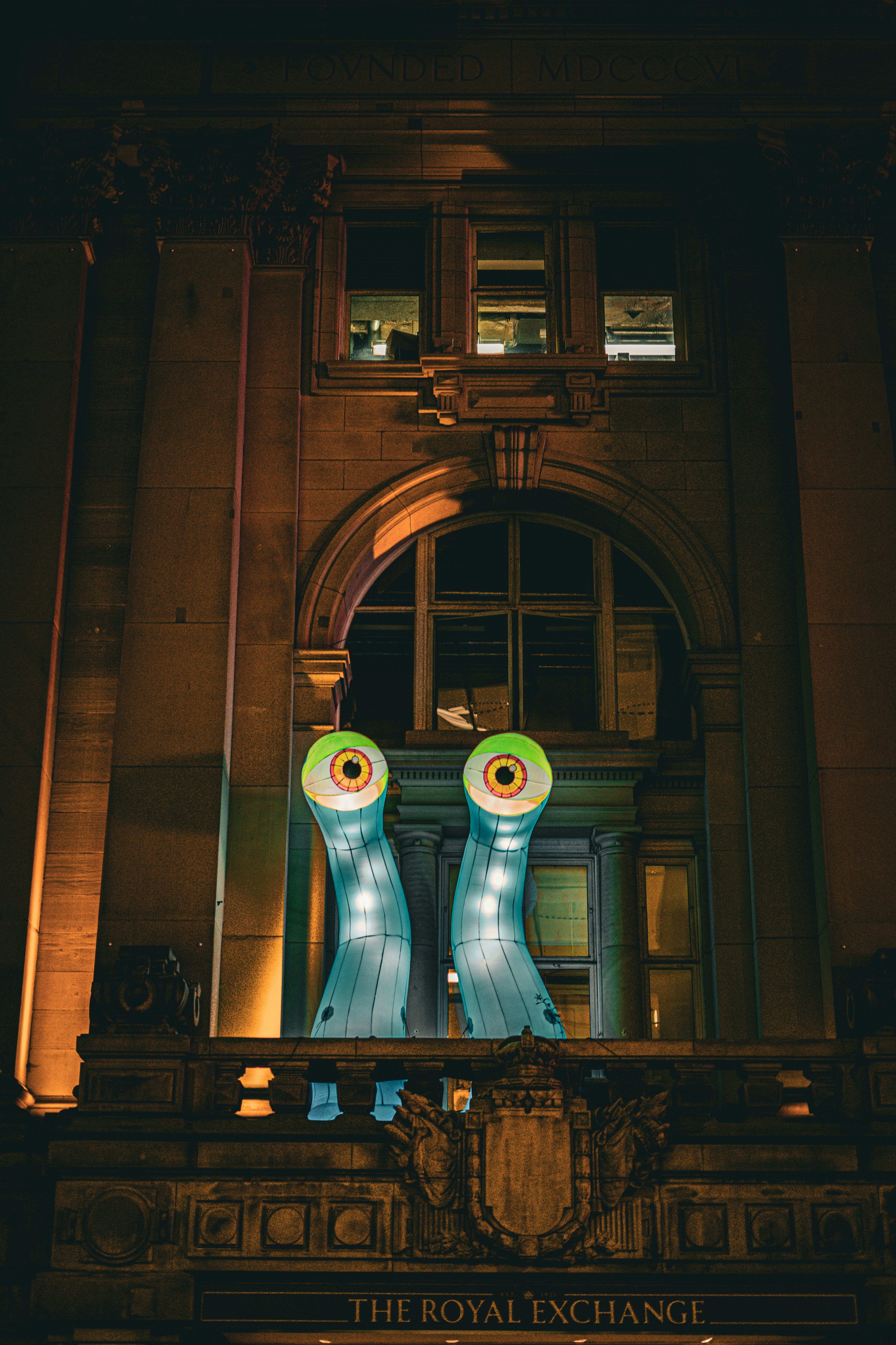 Two glowing inflatable eyeballs emerge from a historic building.