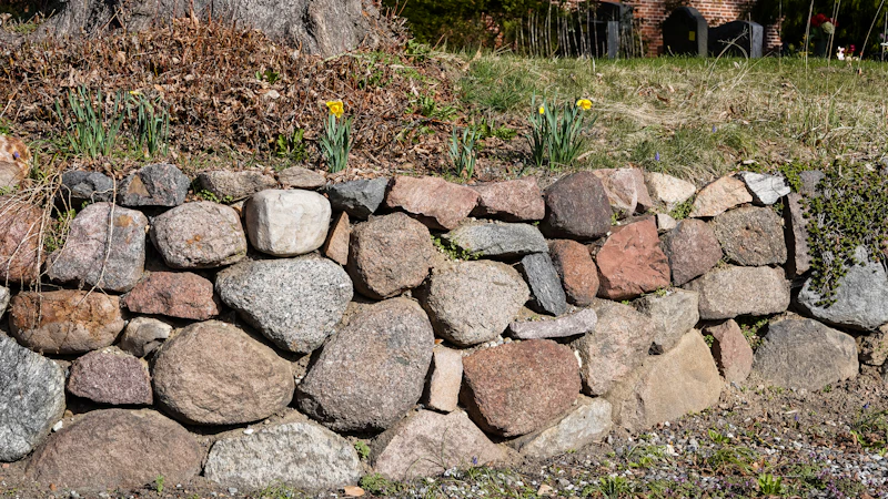A rounded fieldstone retaining wall in a garden.