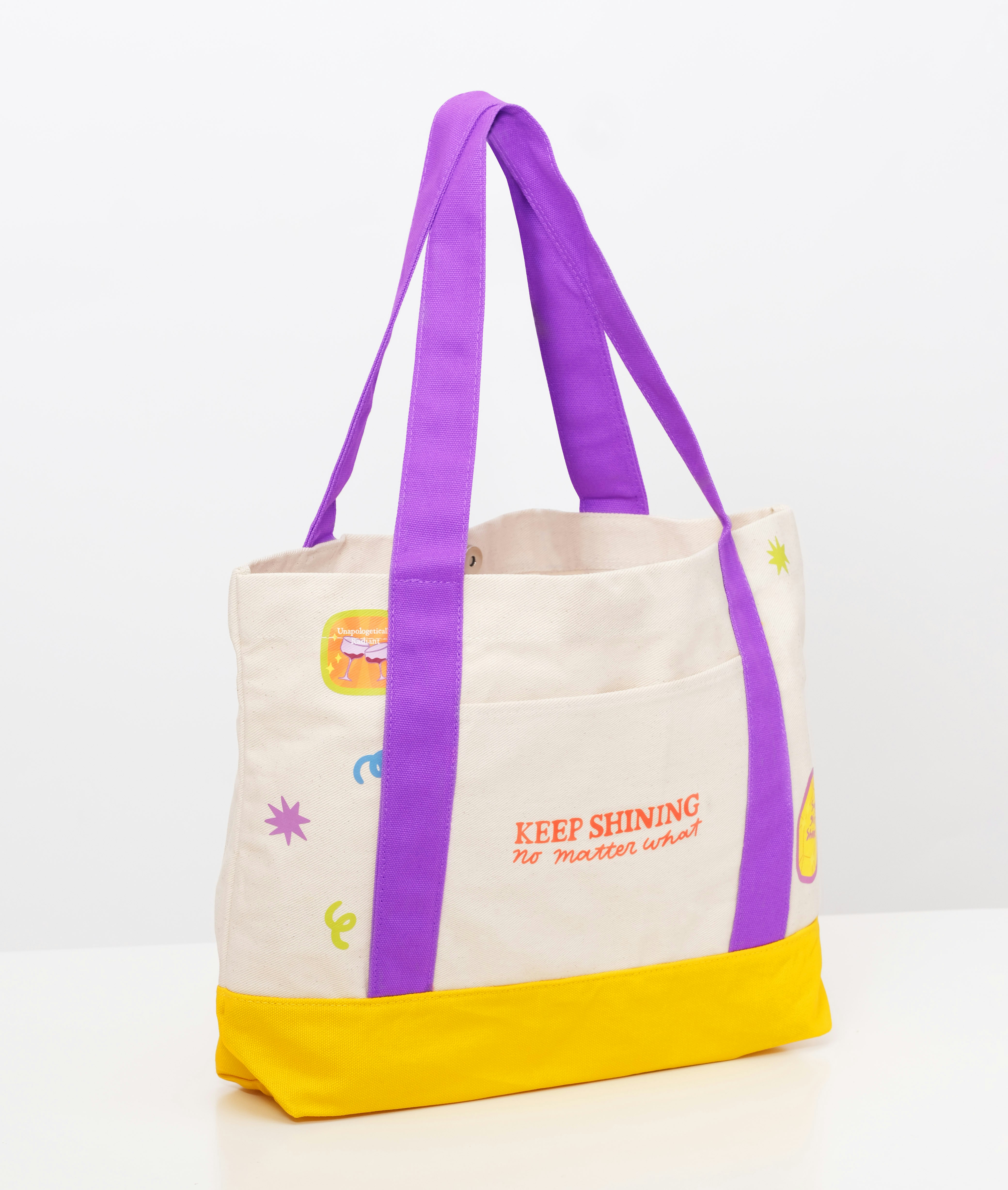Bolsa de lona creme com base amarela e alças roxas.