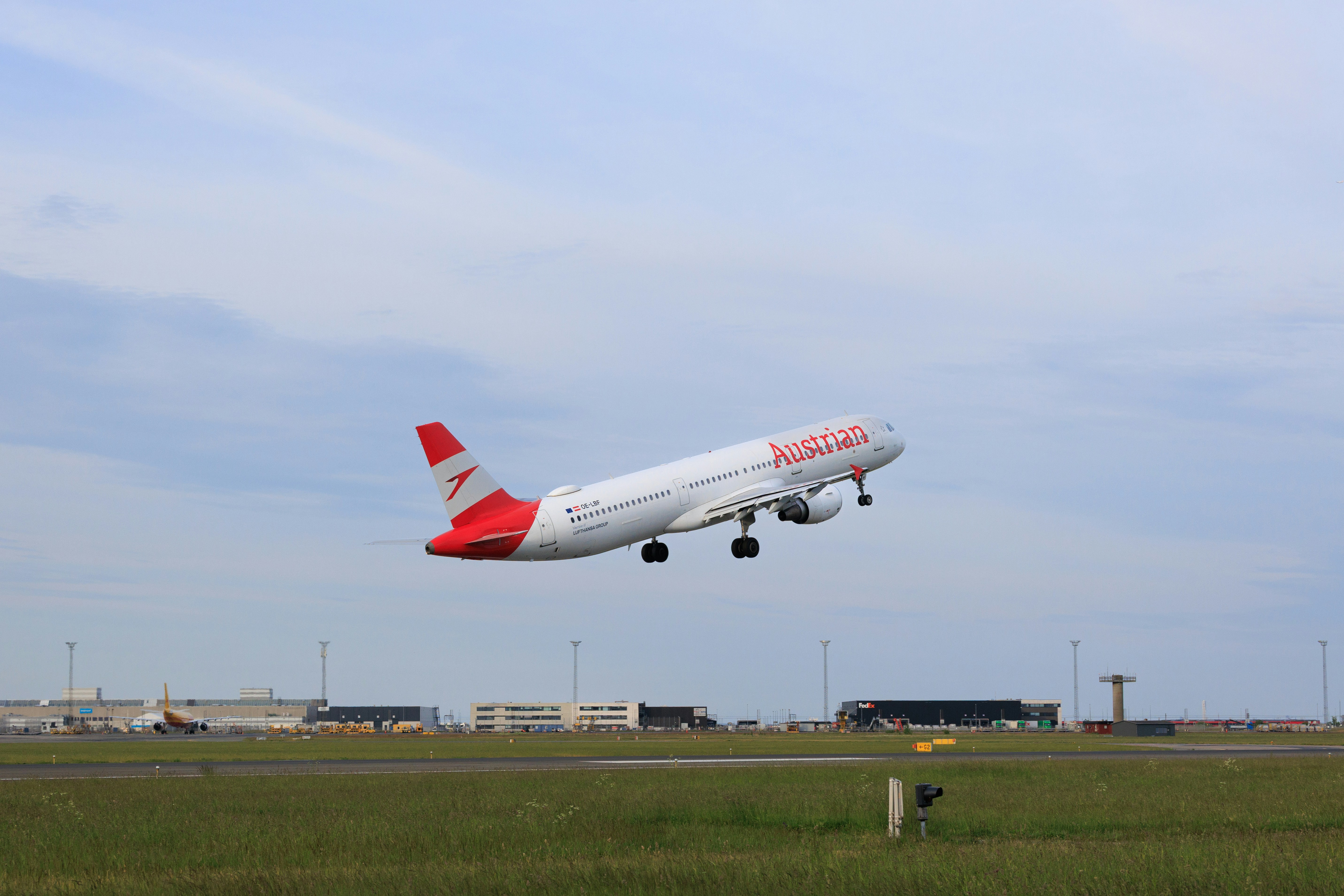 Un avion blanc et rouge décolle d’un aérodrome.