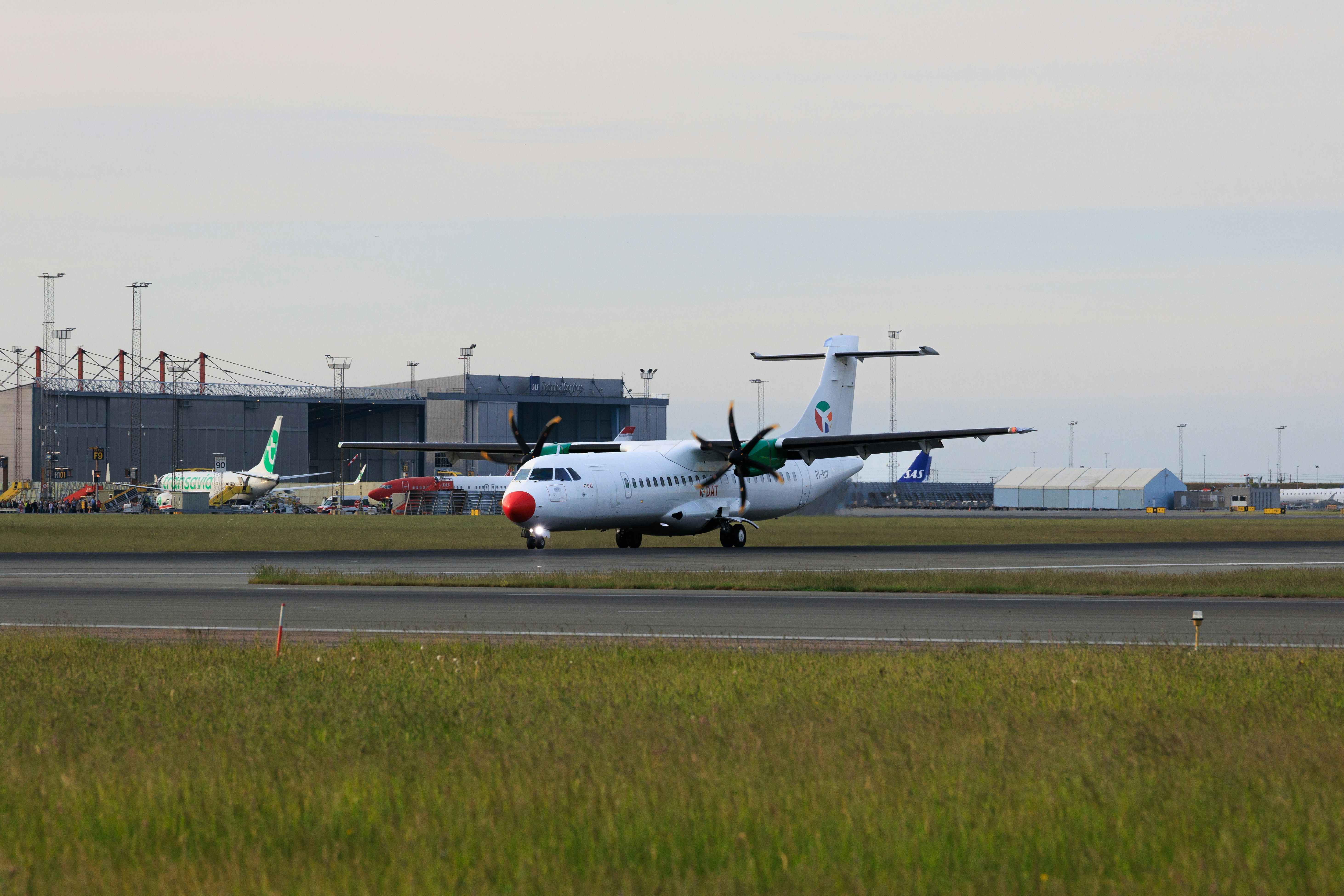 Un avion à turbopropulseur blanc roule sur une piste d’aéroport.