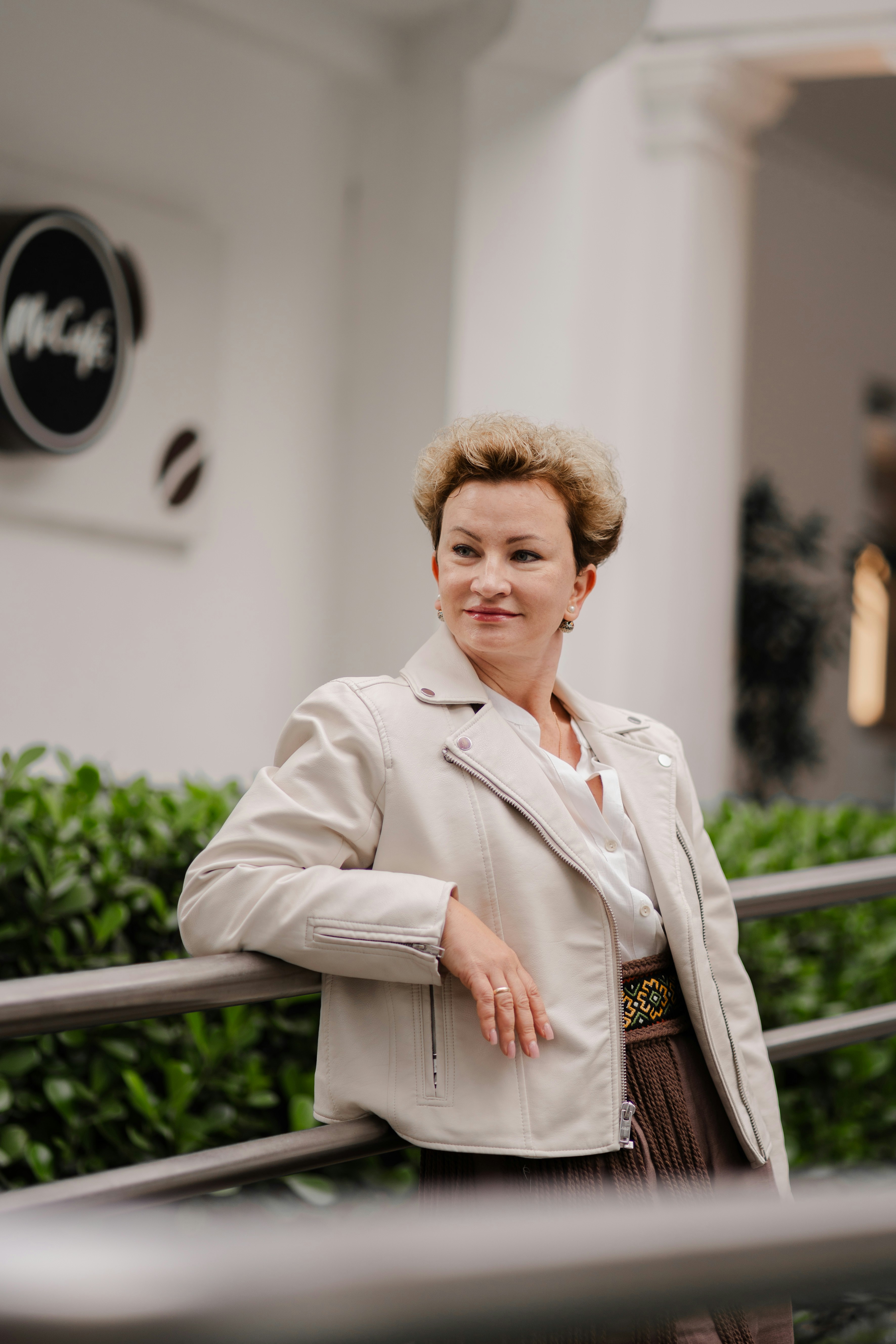 Mujer elegante con chaqueta beige sonríe al aire libre.