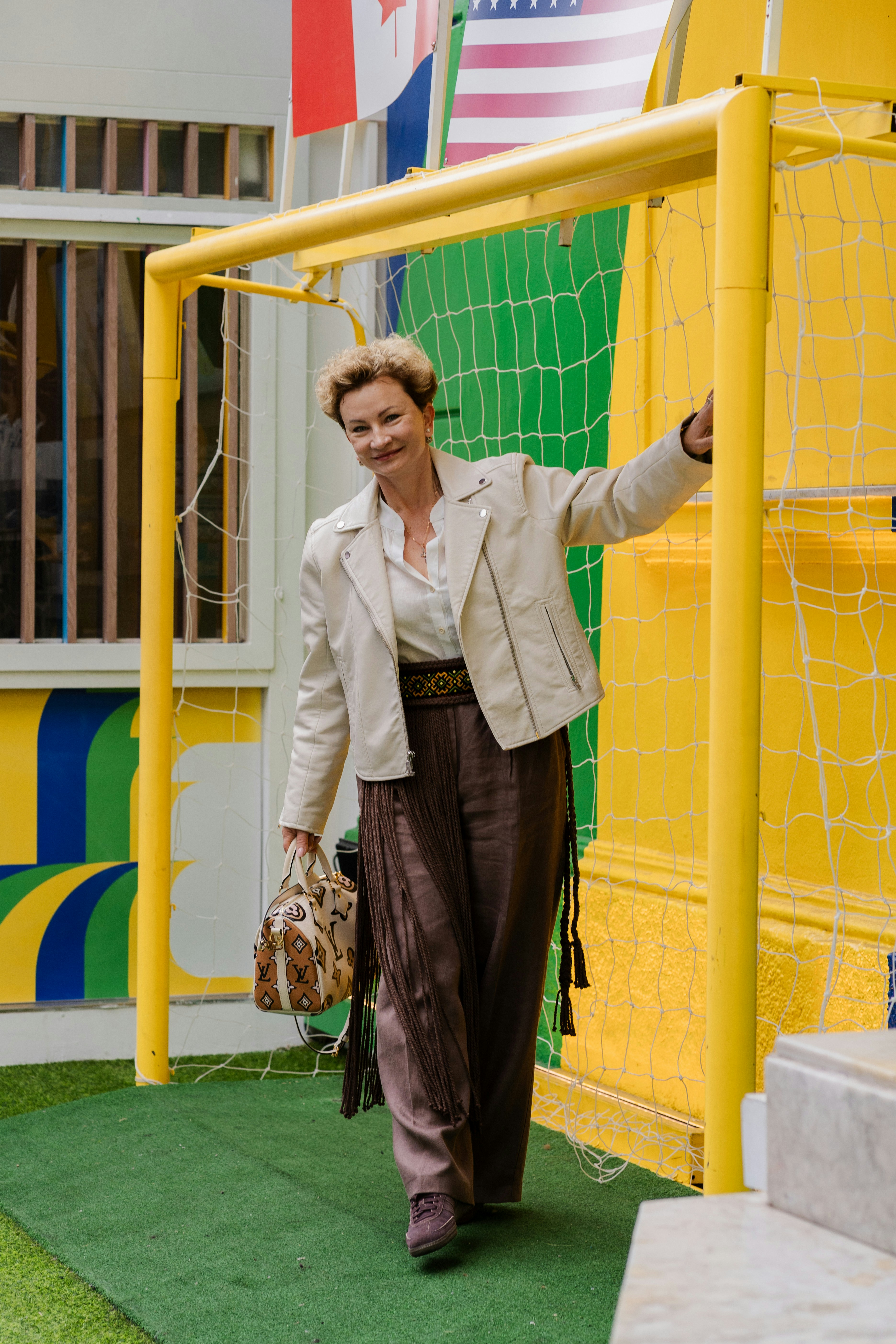 Una mujer está de pie sonriendo en una portería amarilla de fútbol.