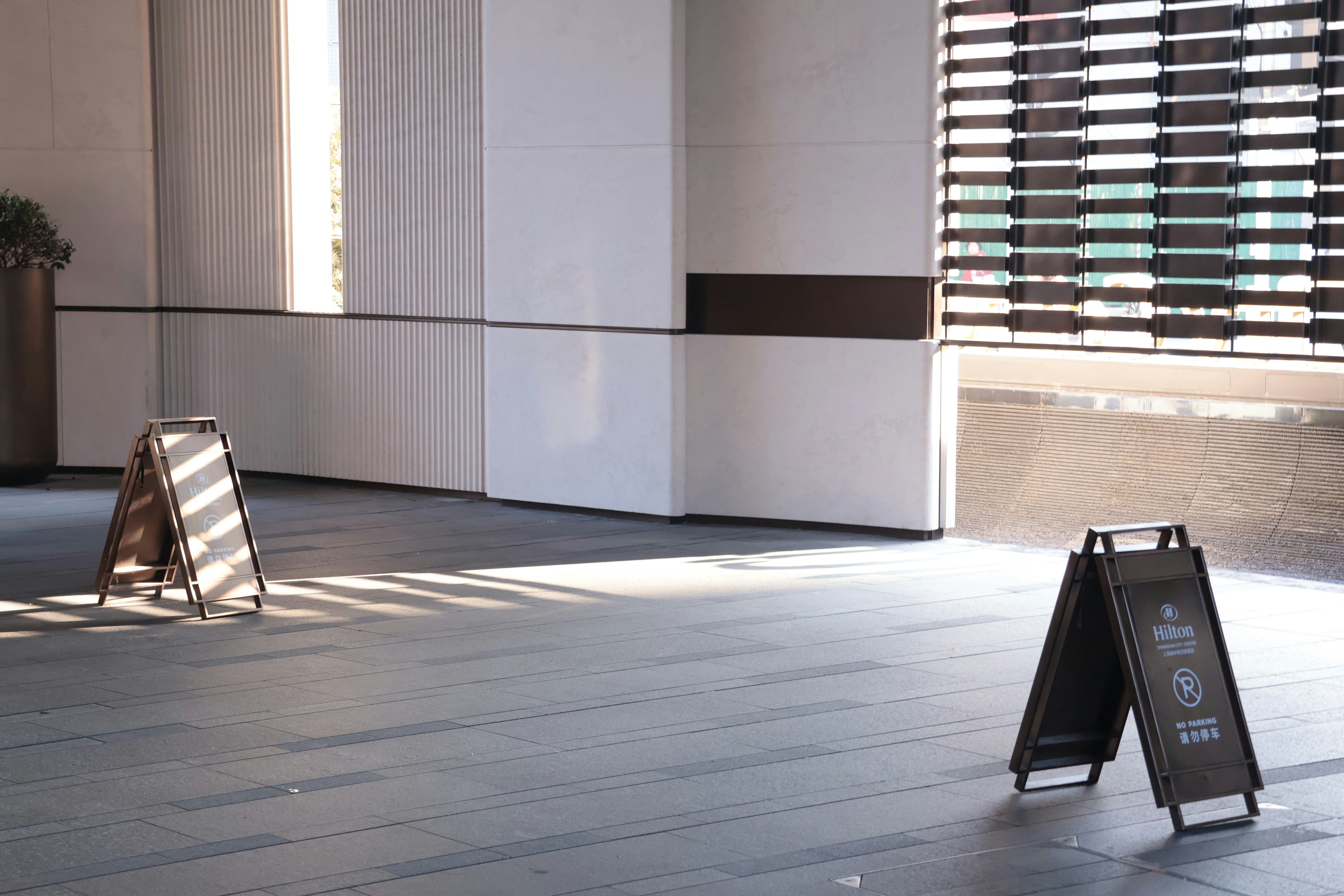 Two a-frame signs on a tiled floor with sunlight.