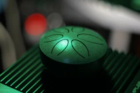 Green metallic tongue drum with etched designs on top.