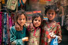 Three young girls posing together in a vibrant market.