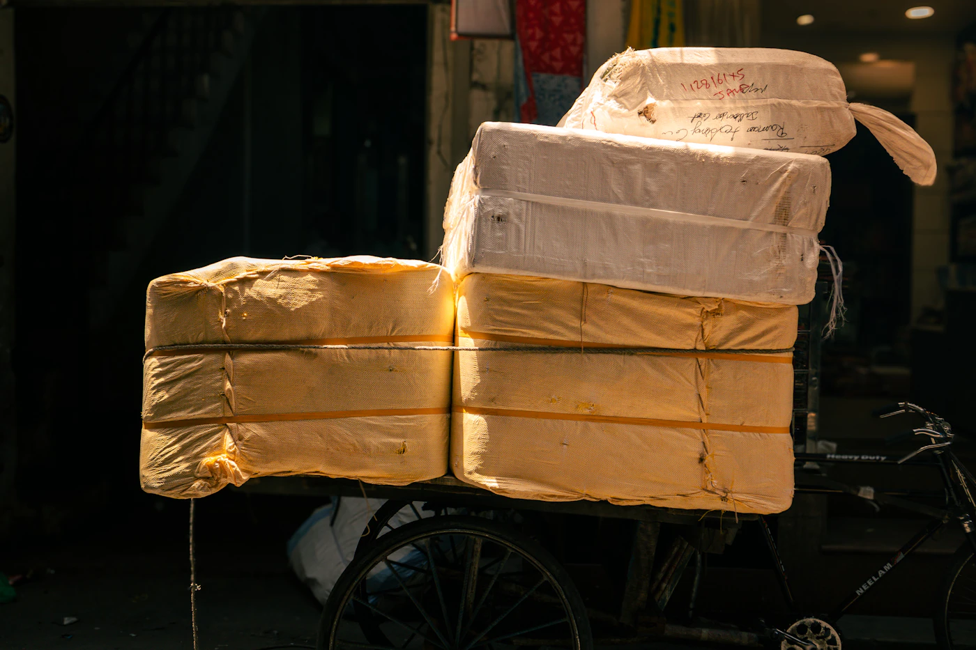 A bicycle loaded with large wrapped parcels moves down a street.