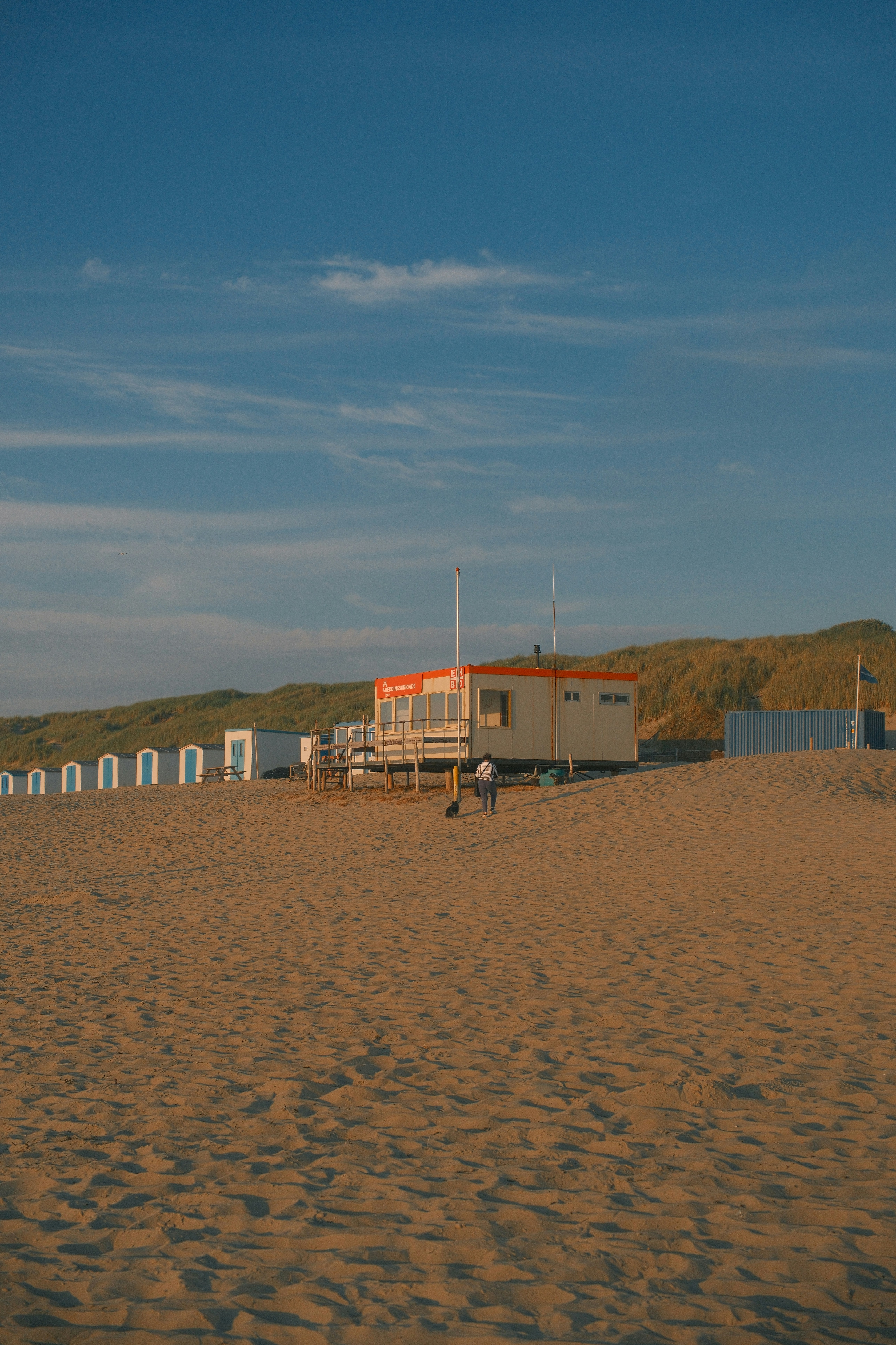 Kleines Gebäude und weiße Hütten an einem Sandstrand.