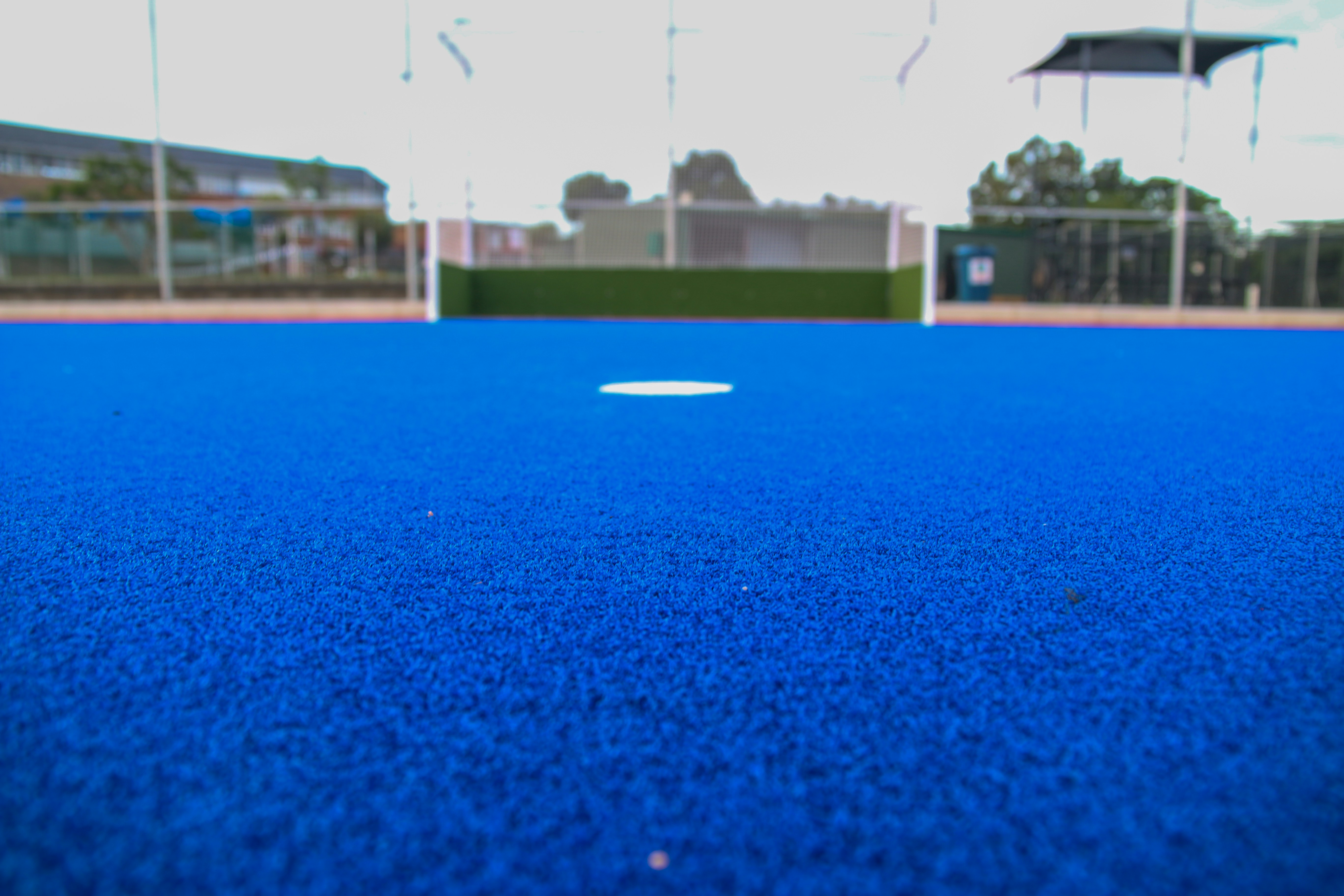 A blue artificial turf field with a hockey goal.