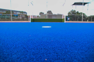 A blue artificial turf field with a hockey goal.