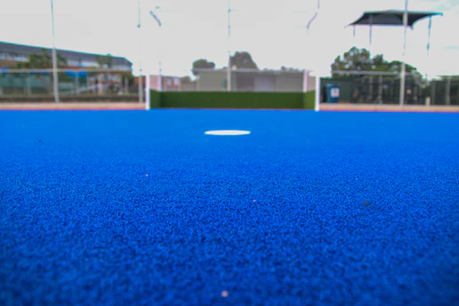 A blue artificial turf field with a hockey goal.