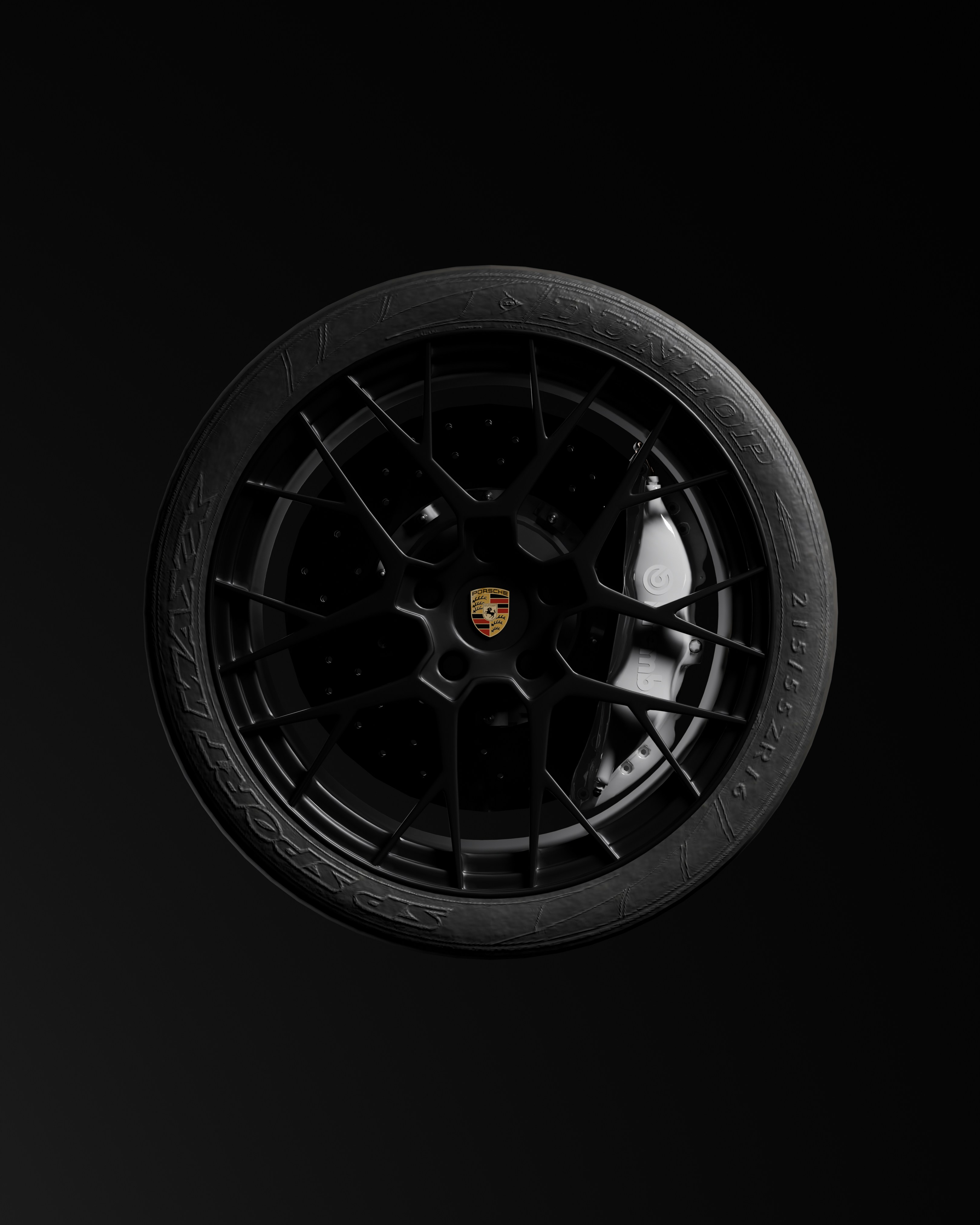 Ein einzelnes schwarzes Porsche-Rad mit goldenem Emblem auf dunklem Hintergrund.