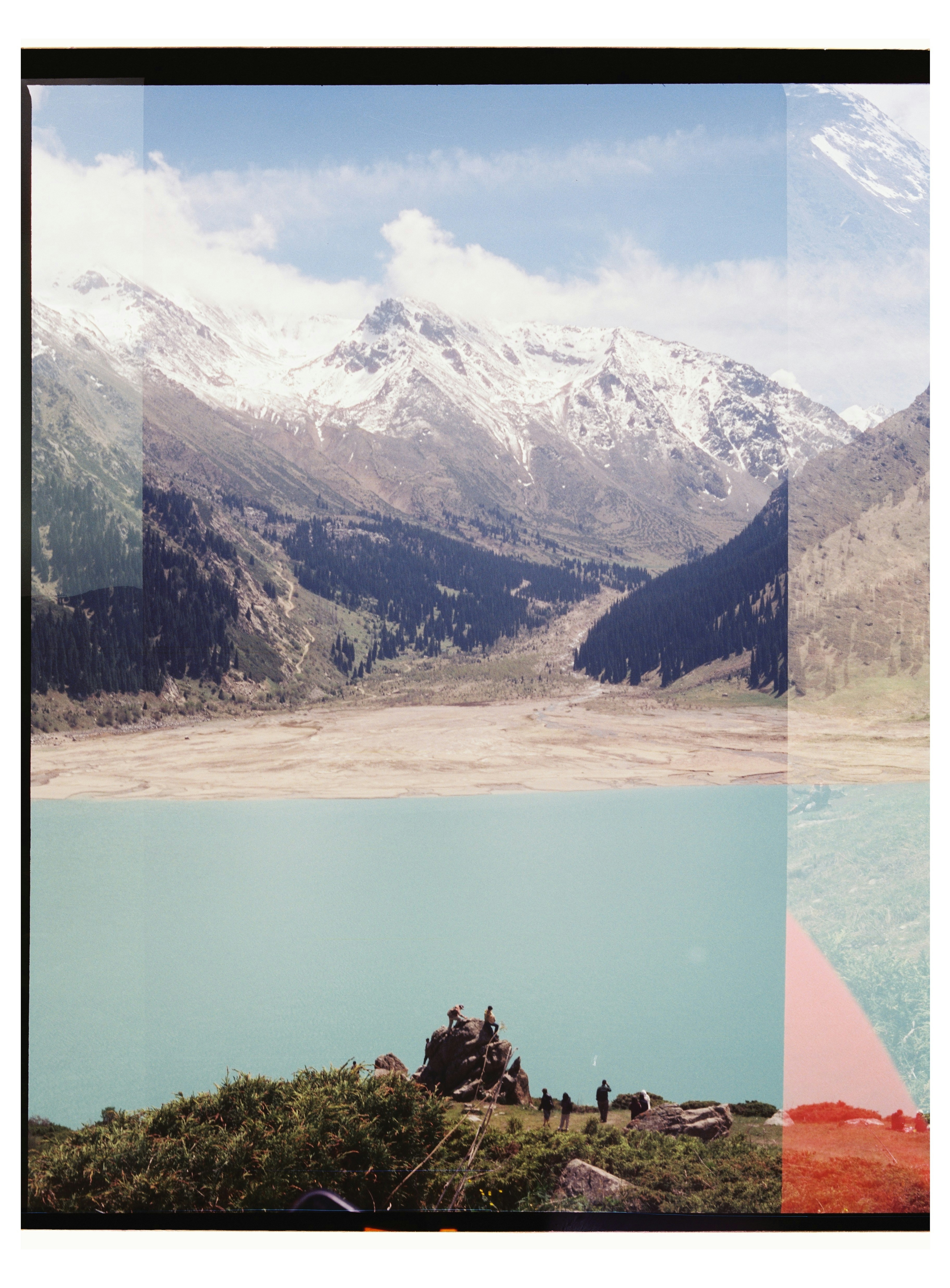 Turquoise lake, snowy mountains, and people on a rocky outcrop.