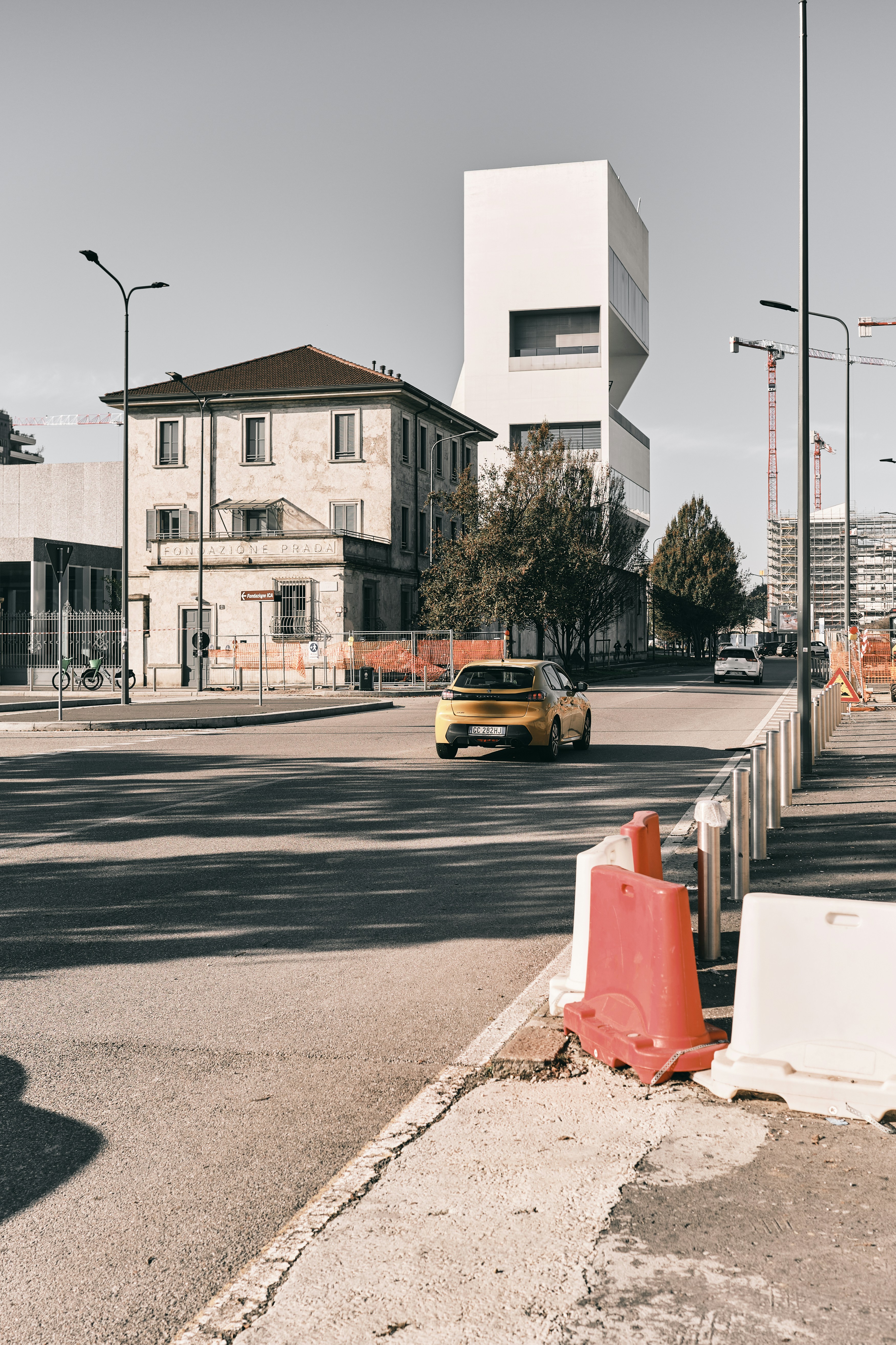 Une voiture jaune passe devant des bâtiments modernes et anciens de la ville.
