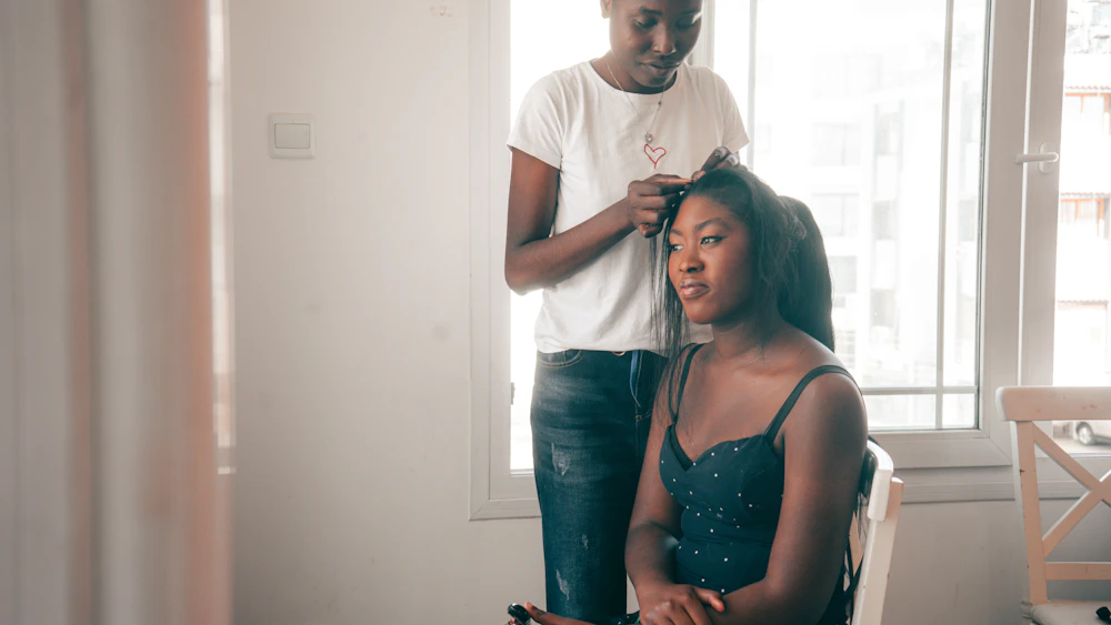 Belle femme noire au salon BBM pendant que la coiffeuse réalise sa coiffure
