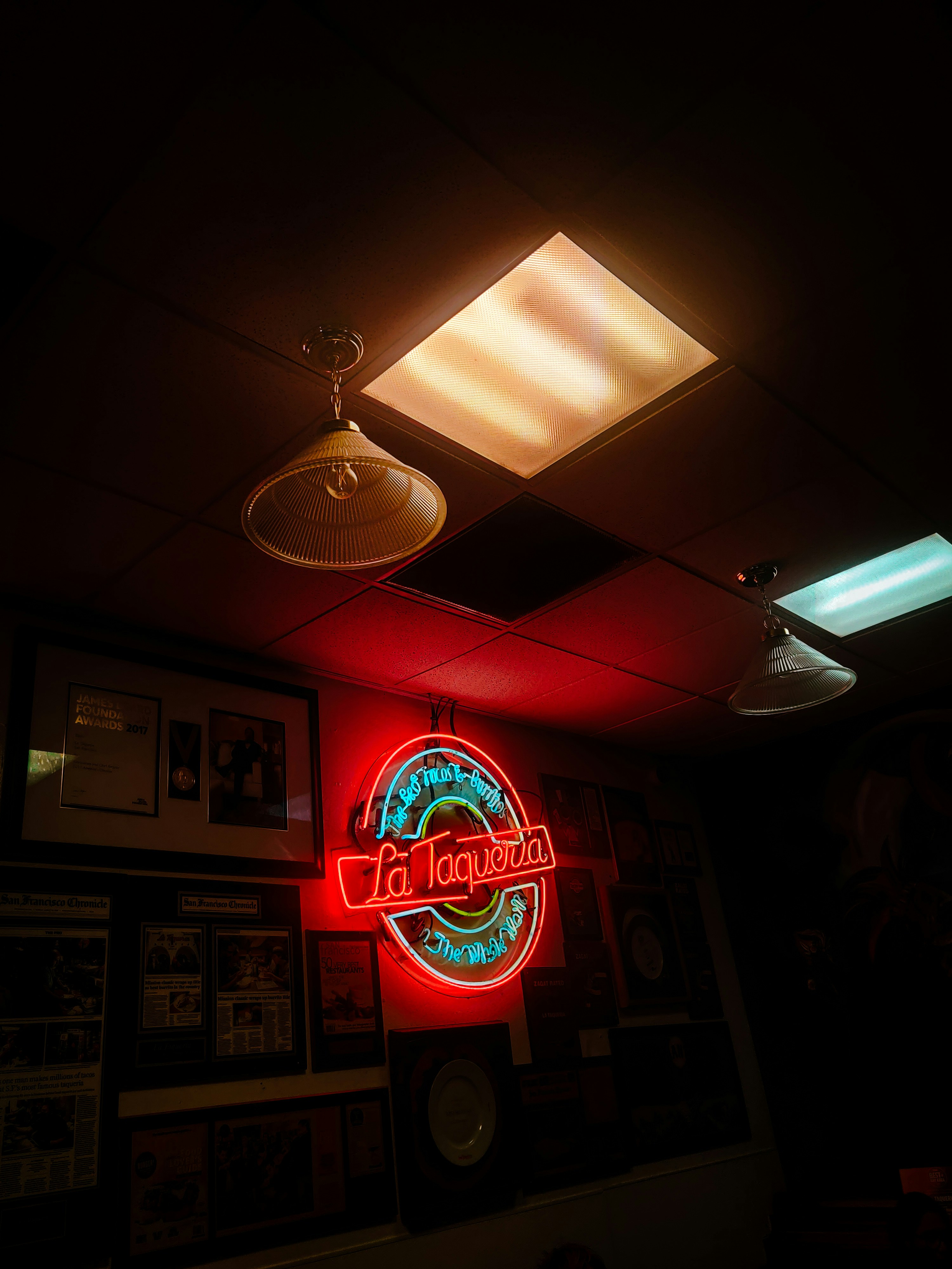 Bright "la taqueria" neon sign on a dark restaurant wall.