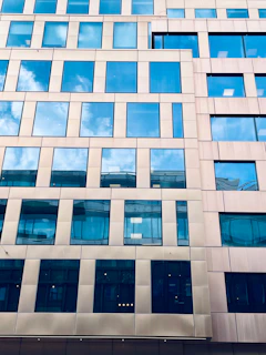Modern building facade with many windows reflecting the blue sky.