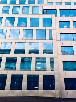 Modern building facade with many windows reflecting the blue sky.