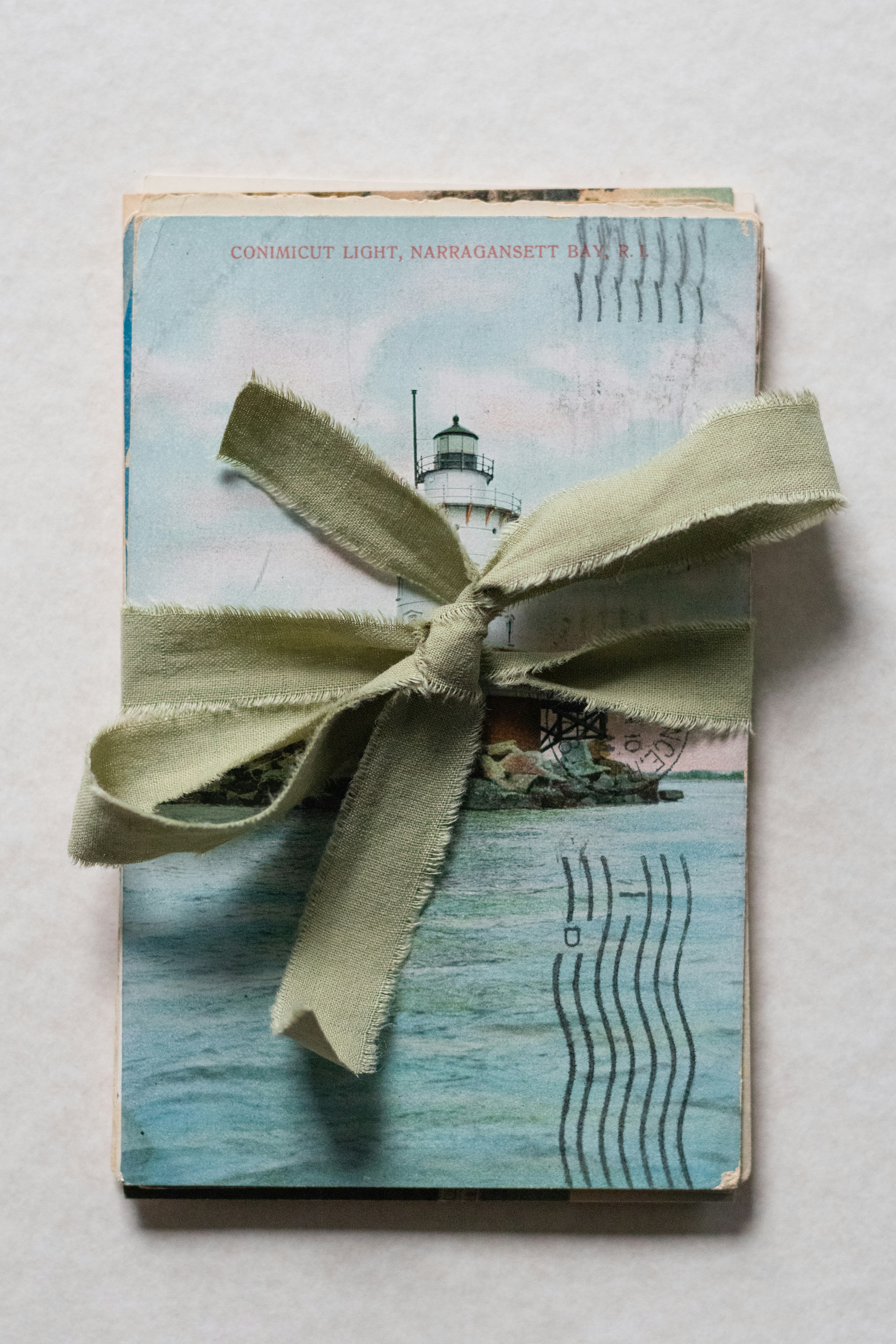 Stack of vintage lighthouse postcards tied with green ribbon.