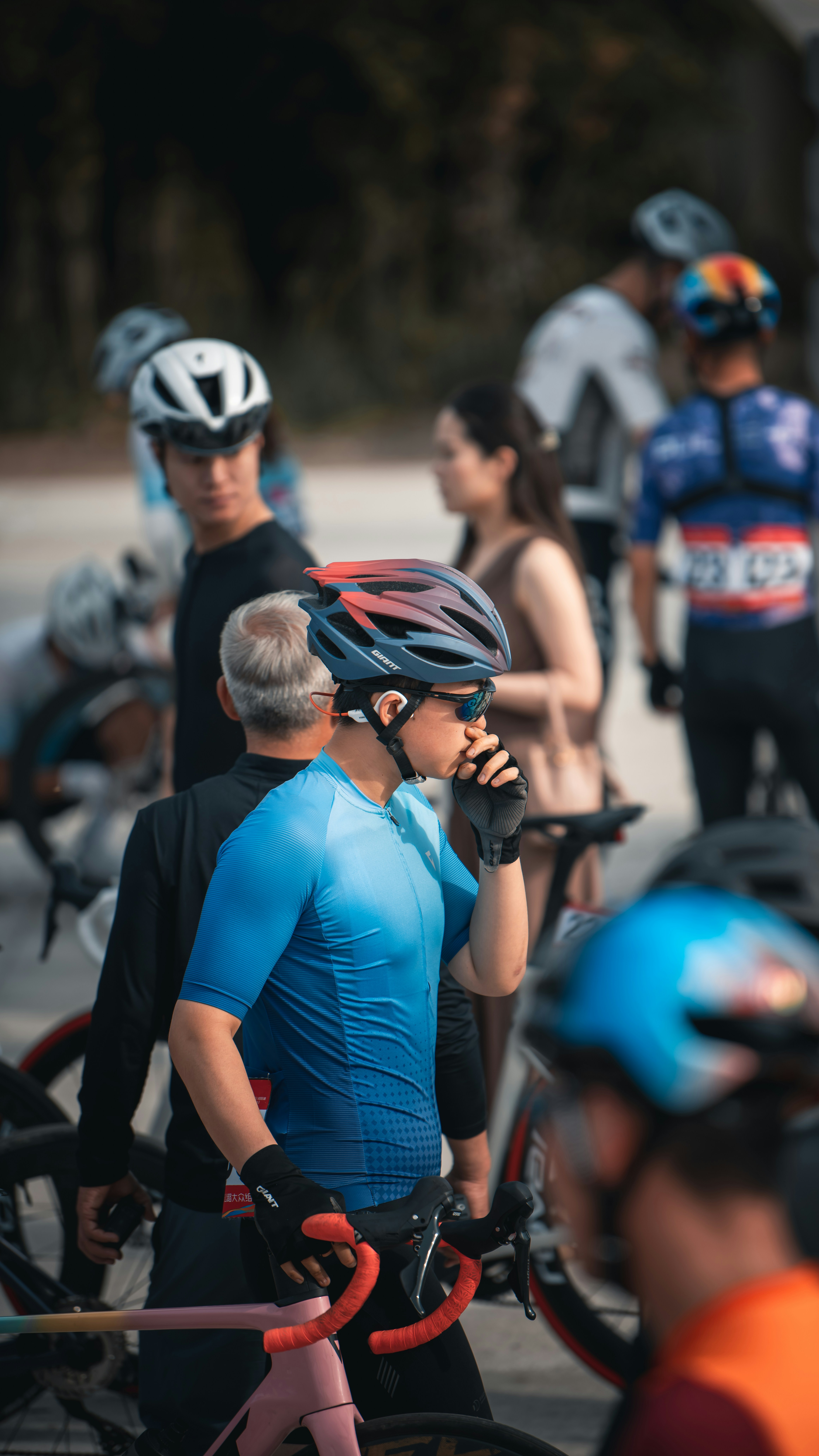 Cyclists in colorful helmets and jerseys gather outdoors.