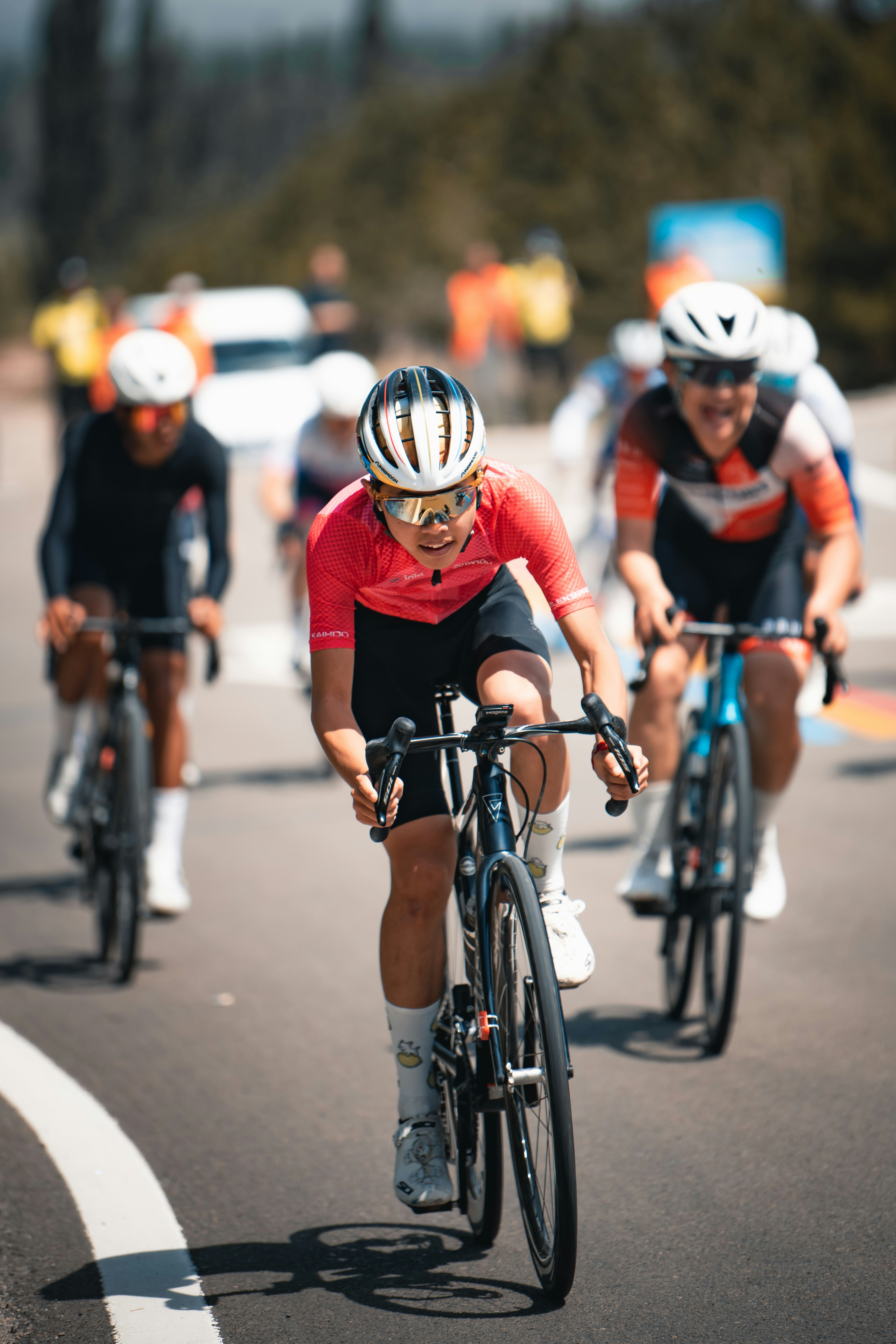 Female cyclist in pink jersey leading a bike race.