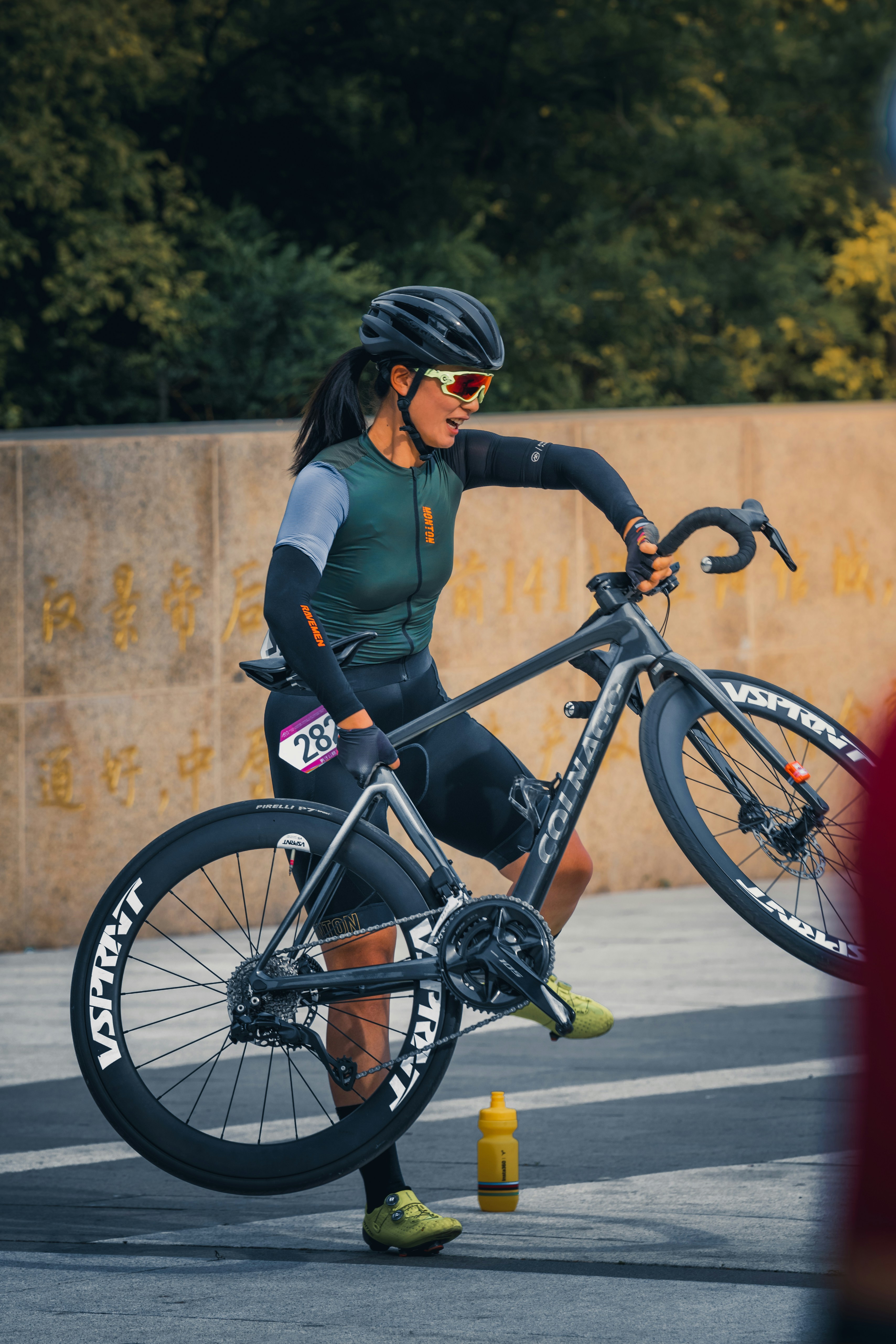 Female cyclist in gear lifts her racing bicycle.