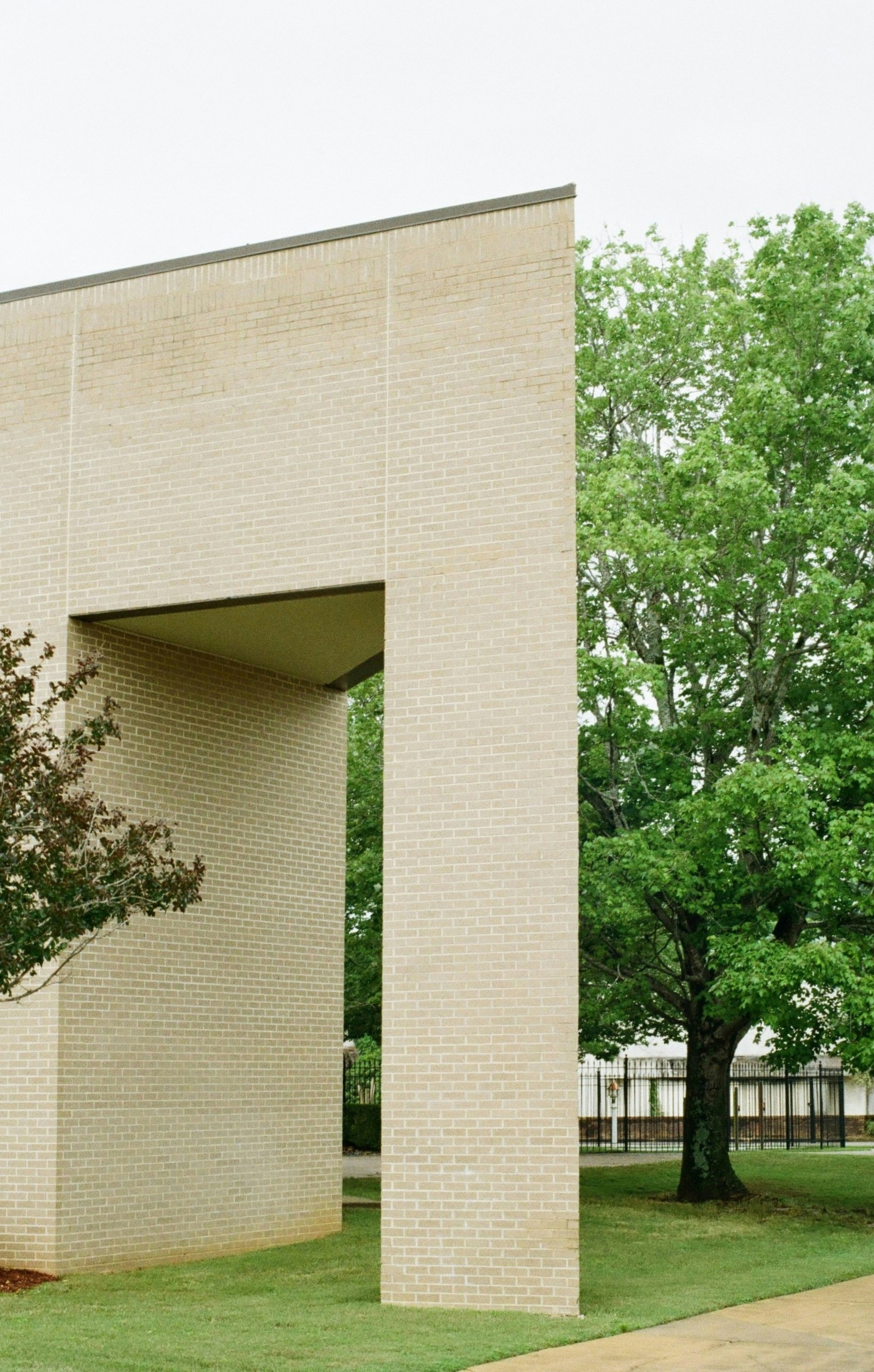 Modern brick building with green trees and grass.