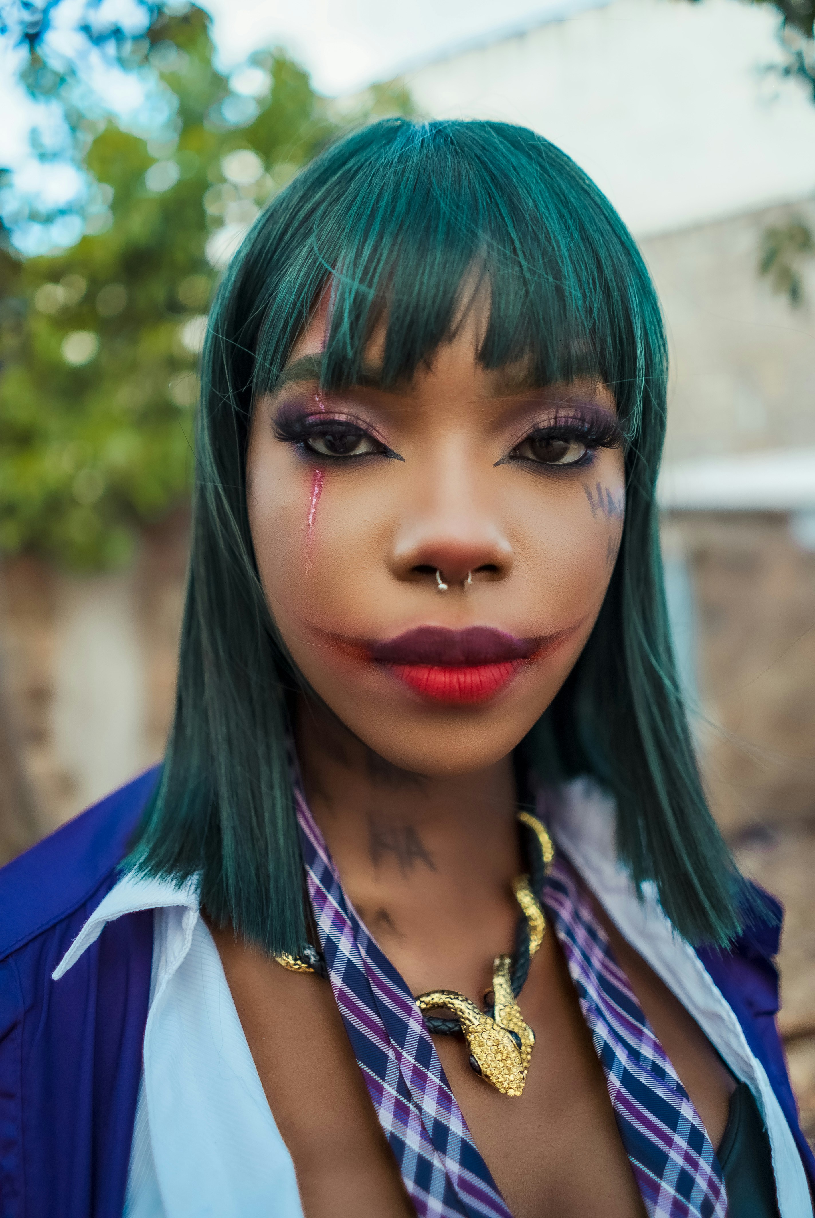 Wanita muda dengan rambut teal dan riasan yang terinspirasi dari joker.