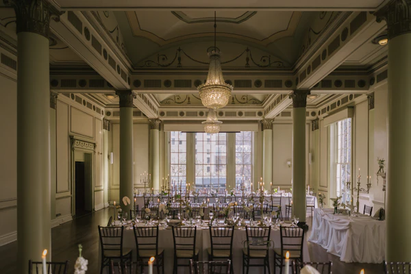 Salón de recepción con mesas largas, candelabros y columnas