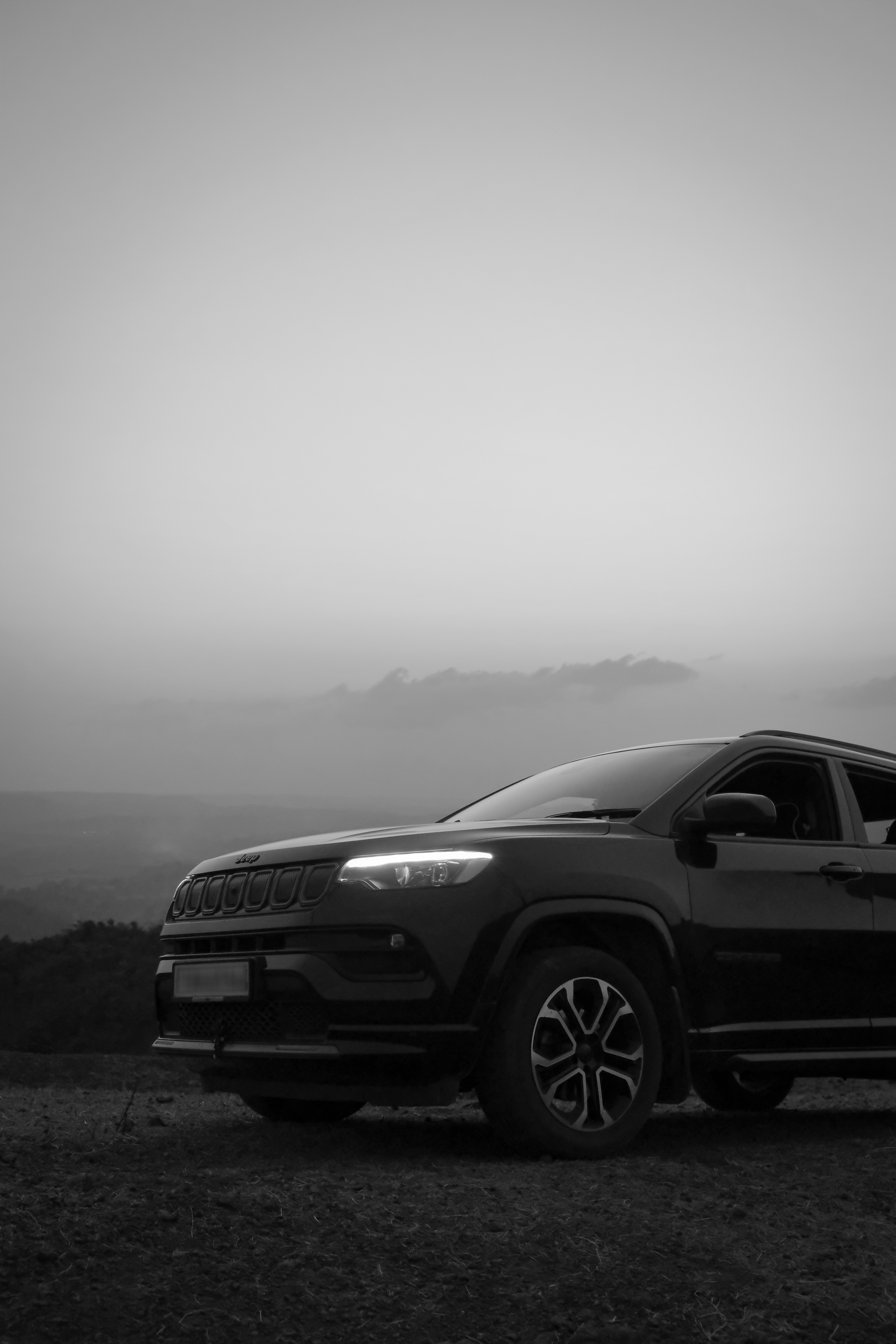 Black suv with bright headlights on a mountain.