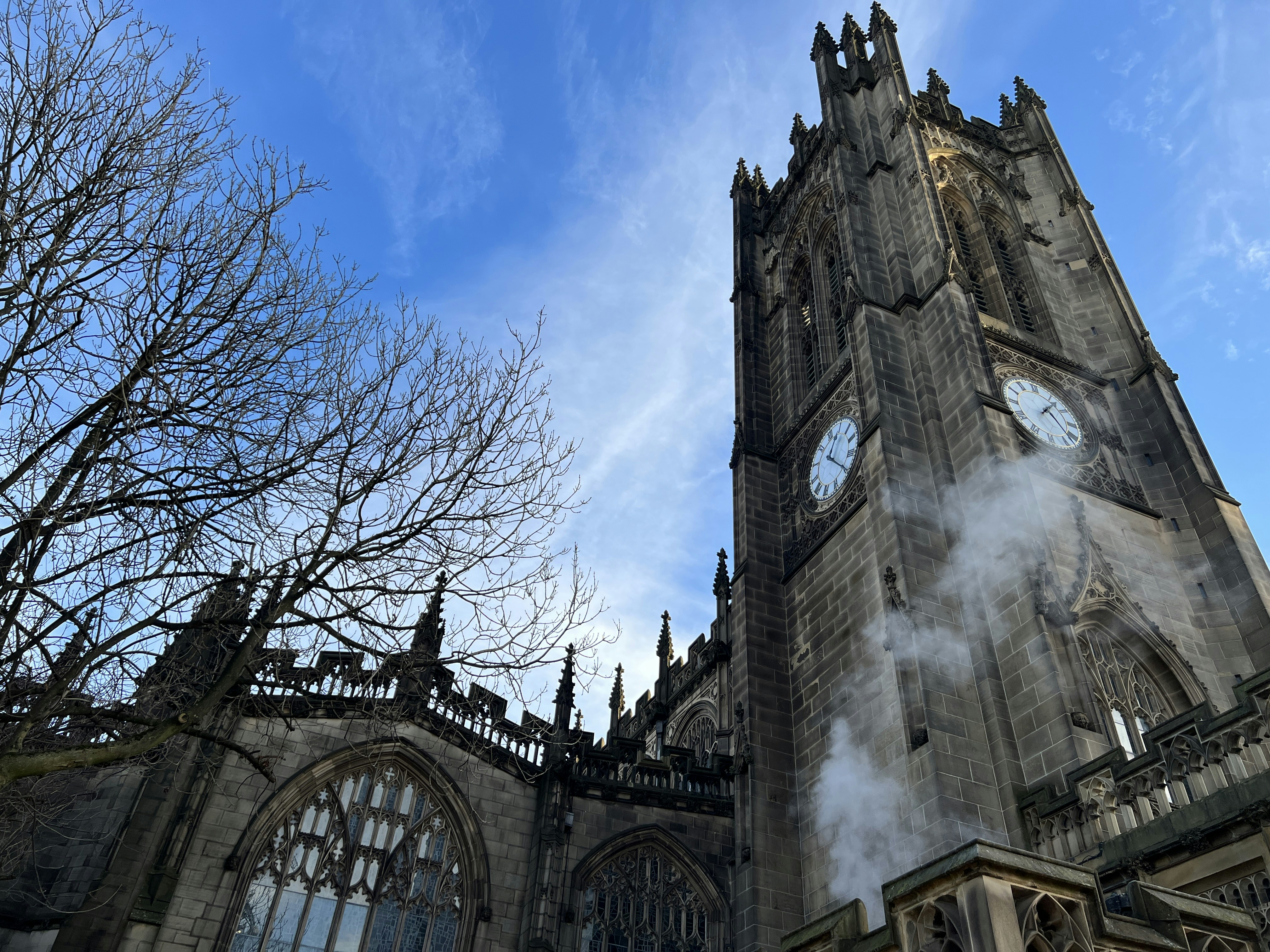 Historic stone church with clock tower and bare trees.