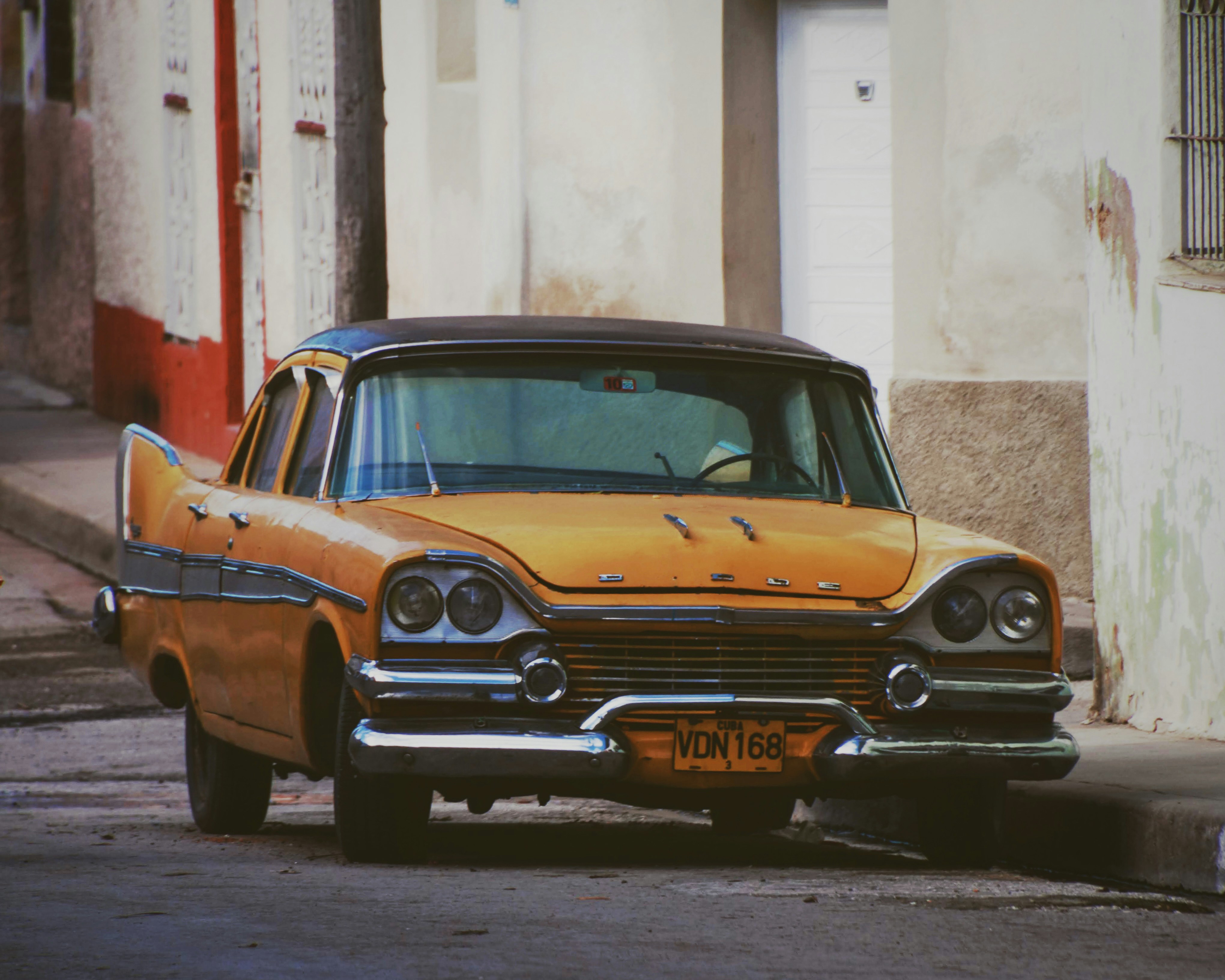 Classic yellow car with a black roof on a street.