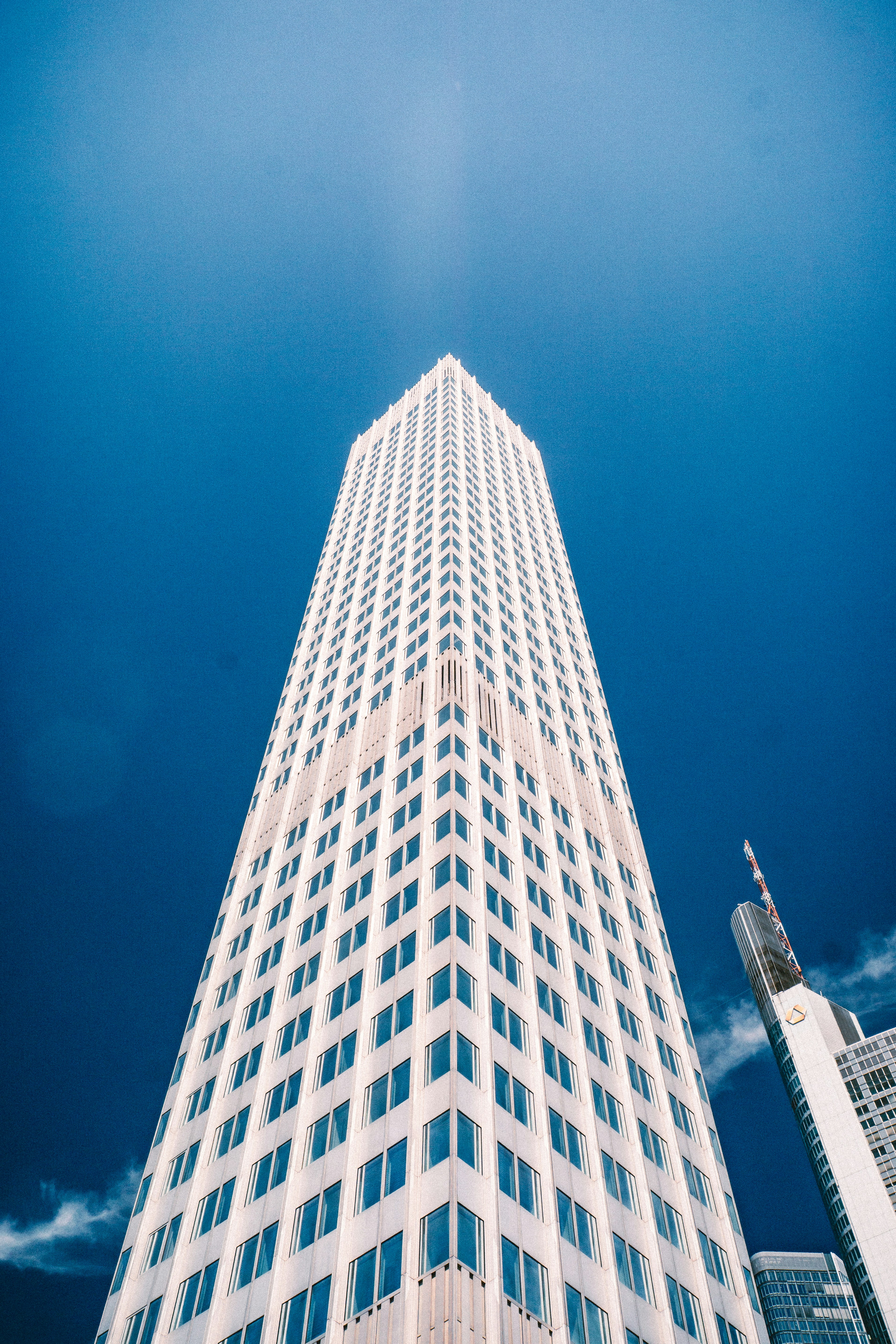 Tall white skyscraper against a clear blue sky.